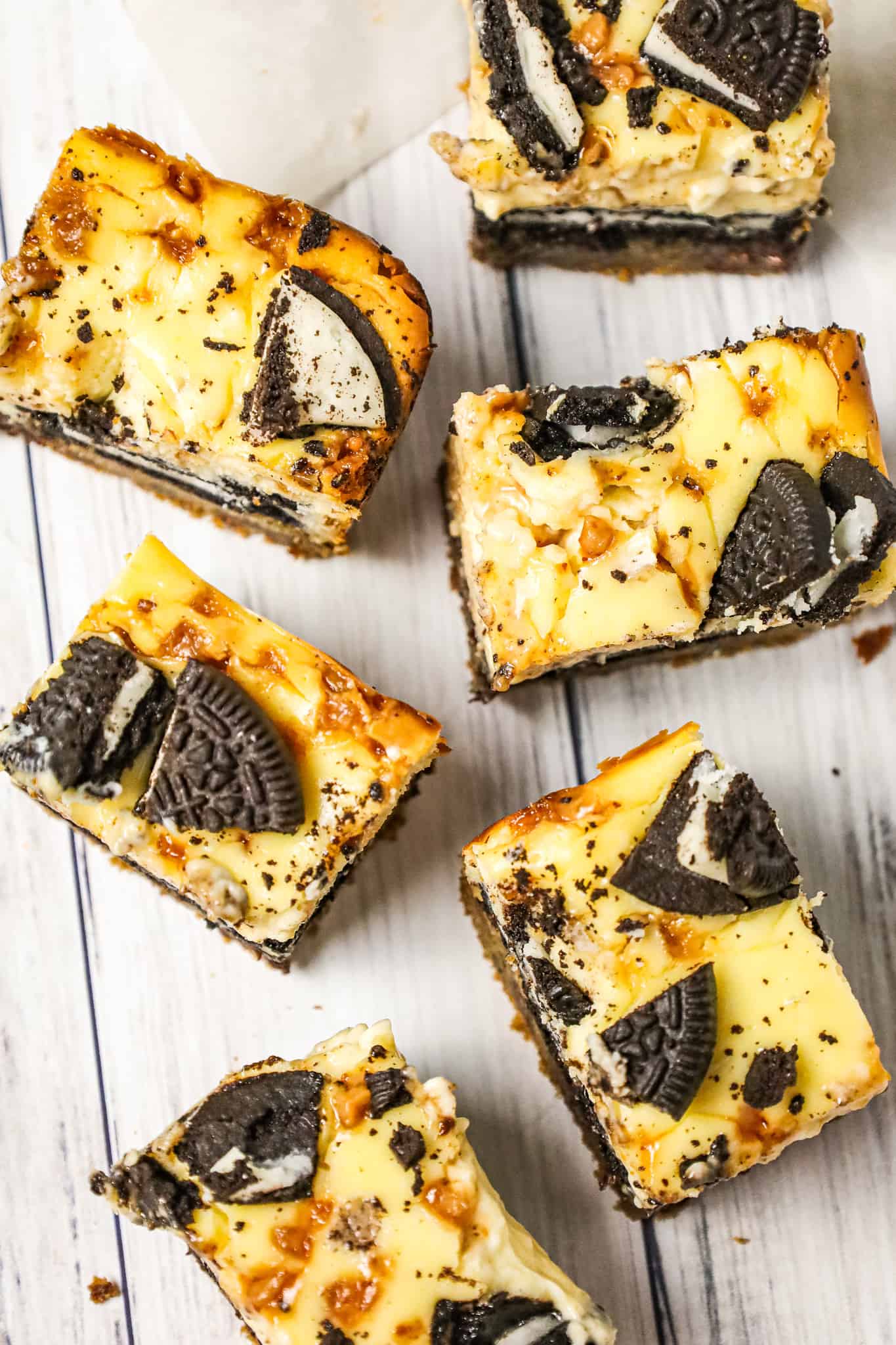Slutty Cheesecake Bars are a decadent dessert recipe with a base of chocolate chip cookie dough topped with Oreo cookies, cheesecake and Skor toffee bits.