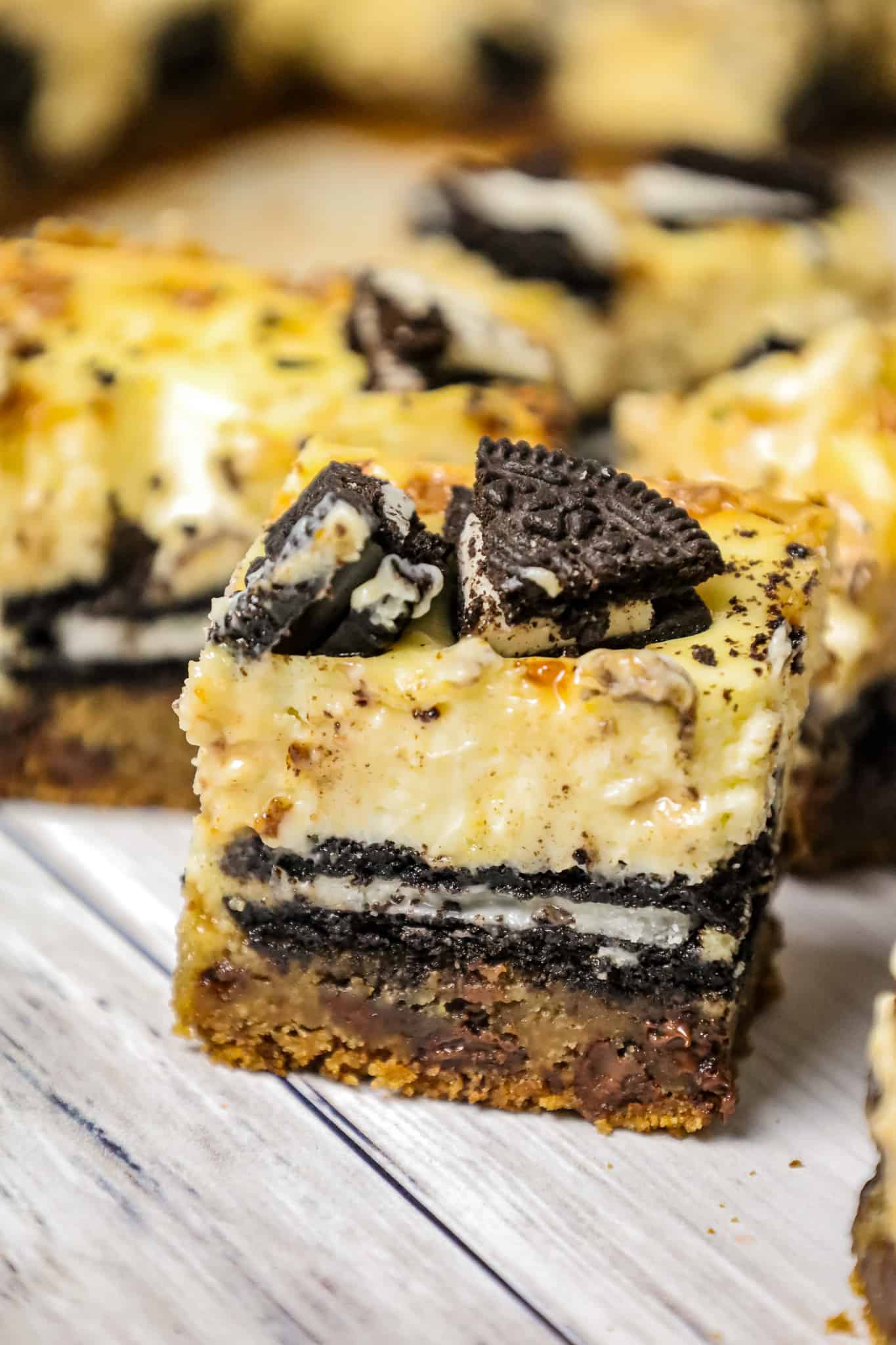 Slutty Cheesecake Bars are a decadent dessert recipe with a base of chocolate chip cookie dough topped with Oreo cookies, cheesecake and Skor toffee bits.