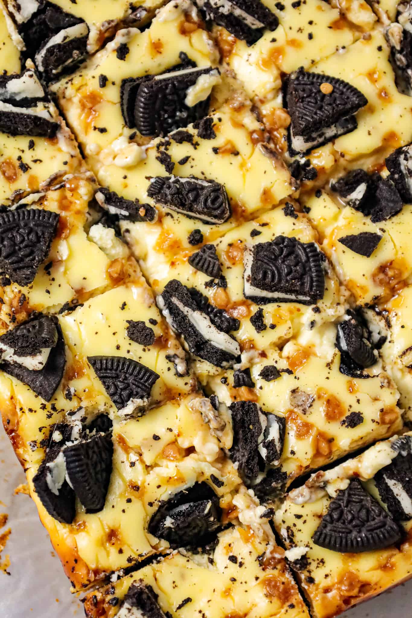 Slutty Cheesecake Bars are a decadent dessert recipe with a base of chocolate chip cookie dough topped with Oreo cookies, cheesecake and Skor toffee bits.