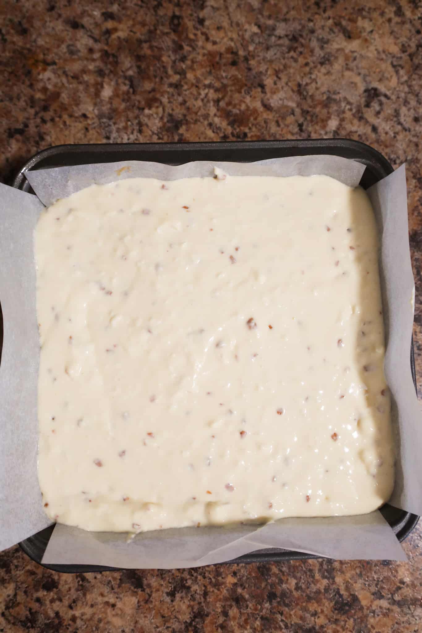 cheesecake mixture in a parchment lined baking pan