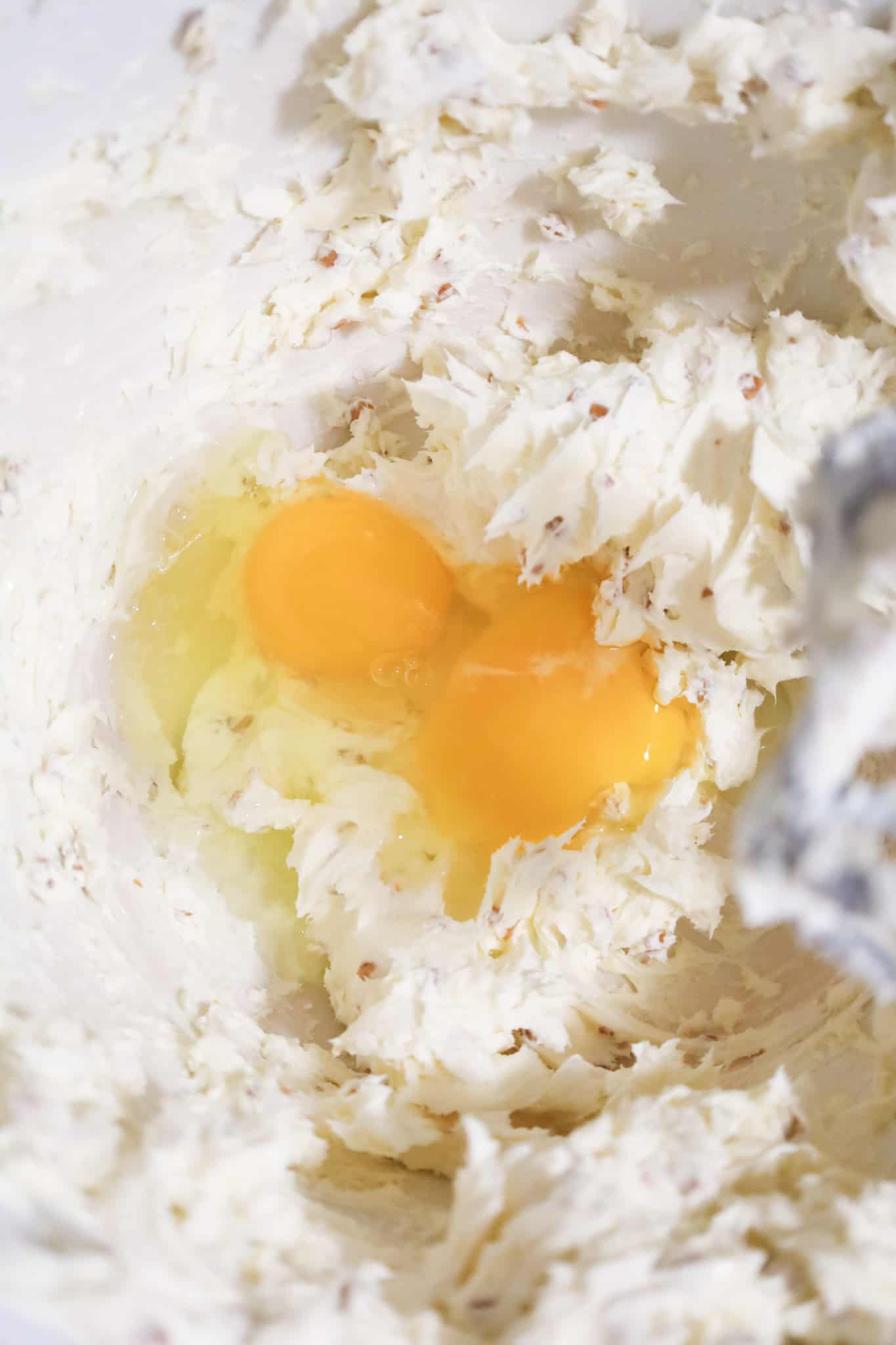 eggs on top of cheesecake mixture in a mixing bowl