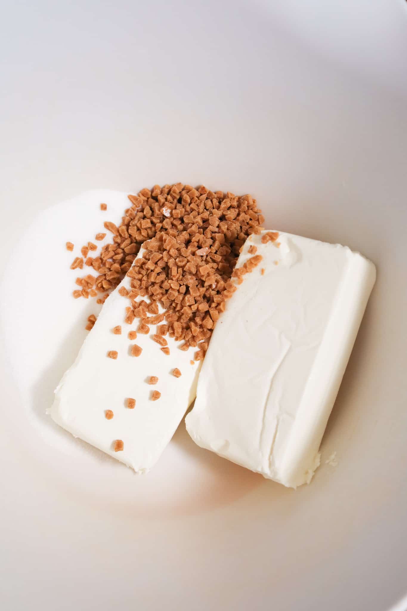 toffee bits on top of cream cheese in a mixing bowl