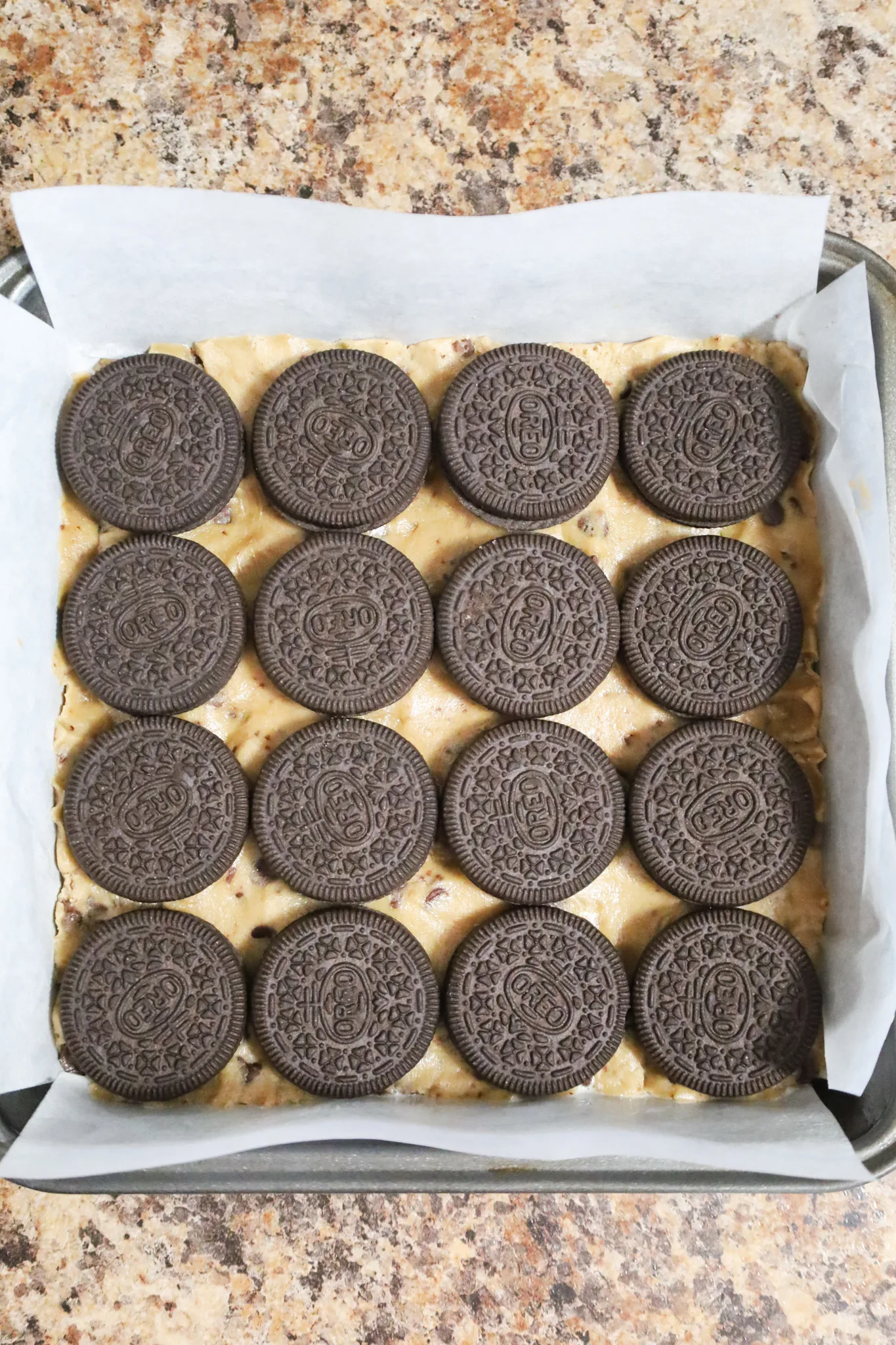 Oreo cookies on top of cookie dough in a parchment lined baking sheet