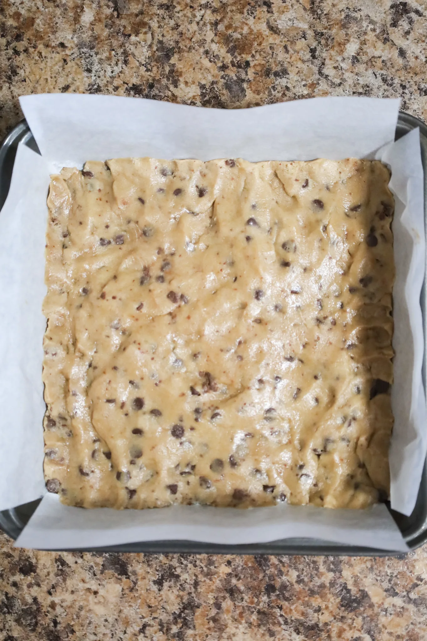 chocolate chip cookie dough pressed into bottom of parchment lined baking dish