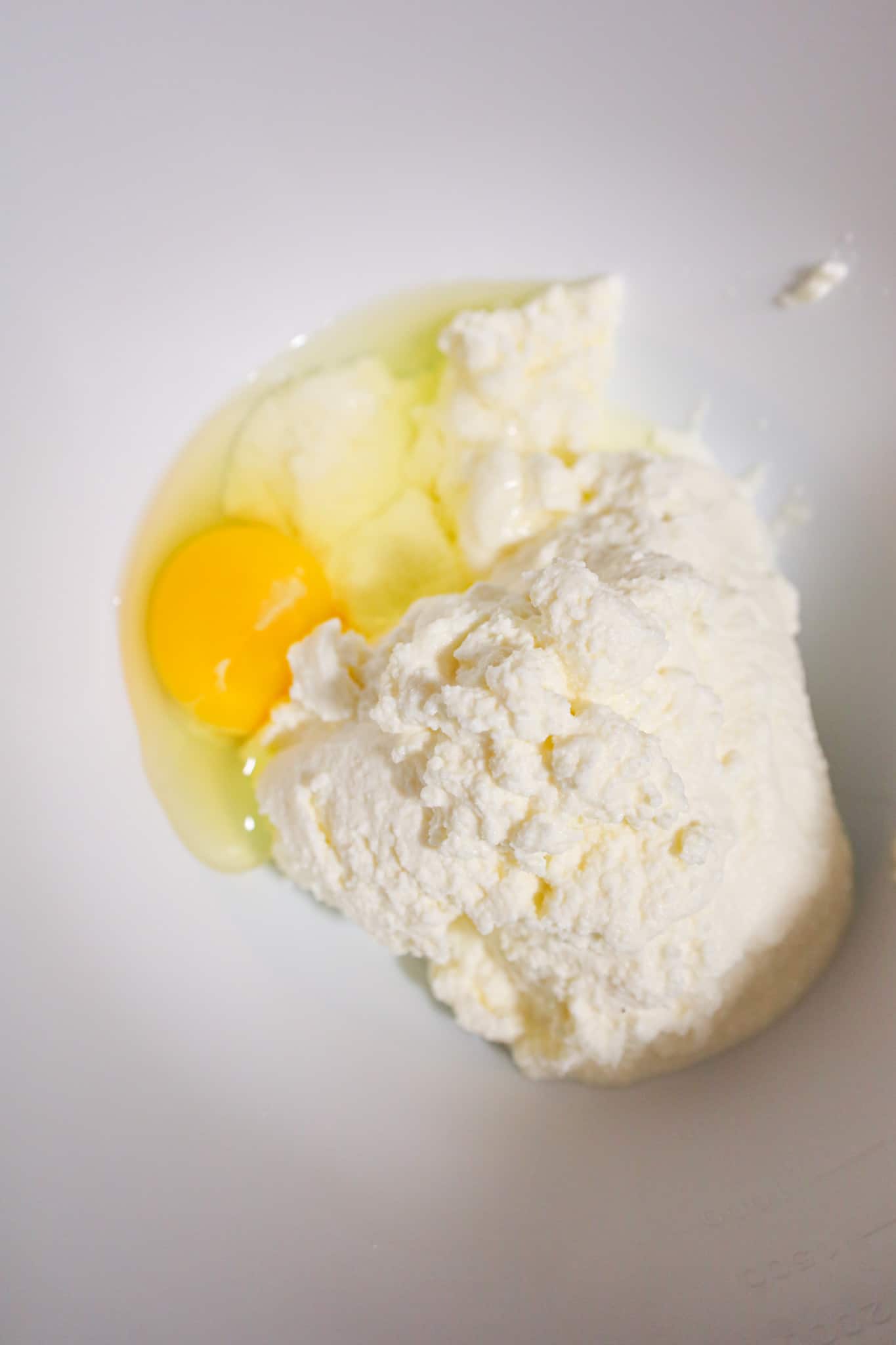 ricotta cheese and an egg in a mixing bowl