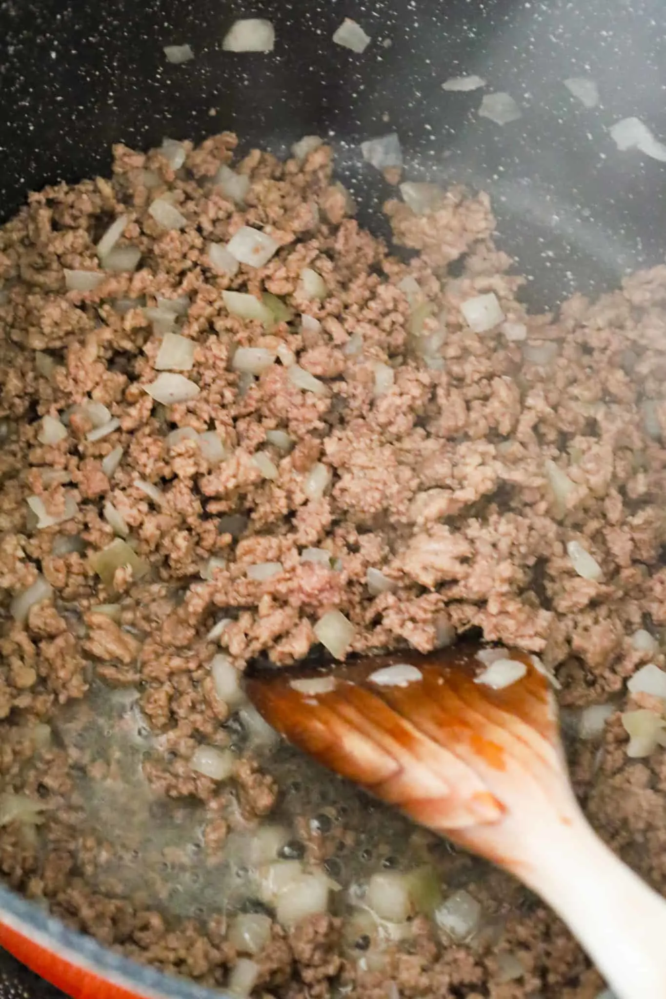 crumbled ground beef and diced onions cooking in a large pot