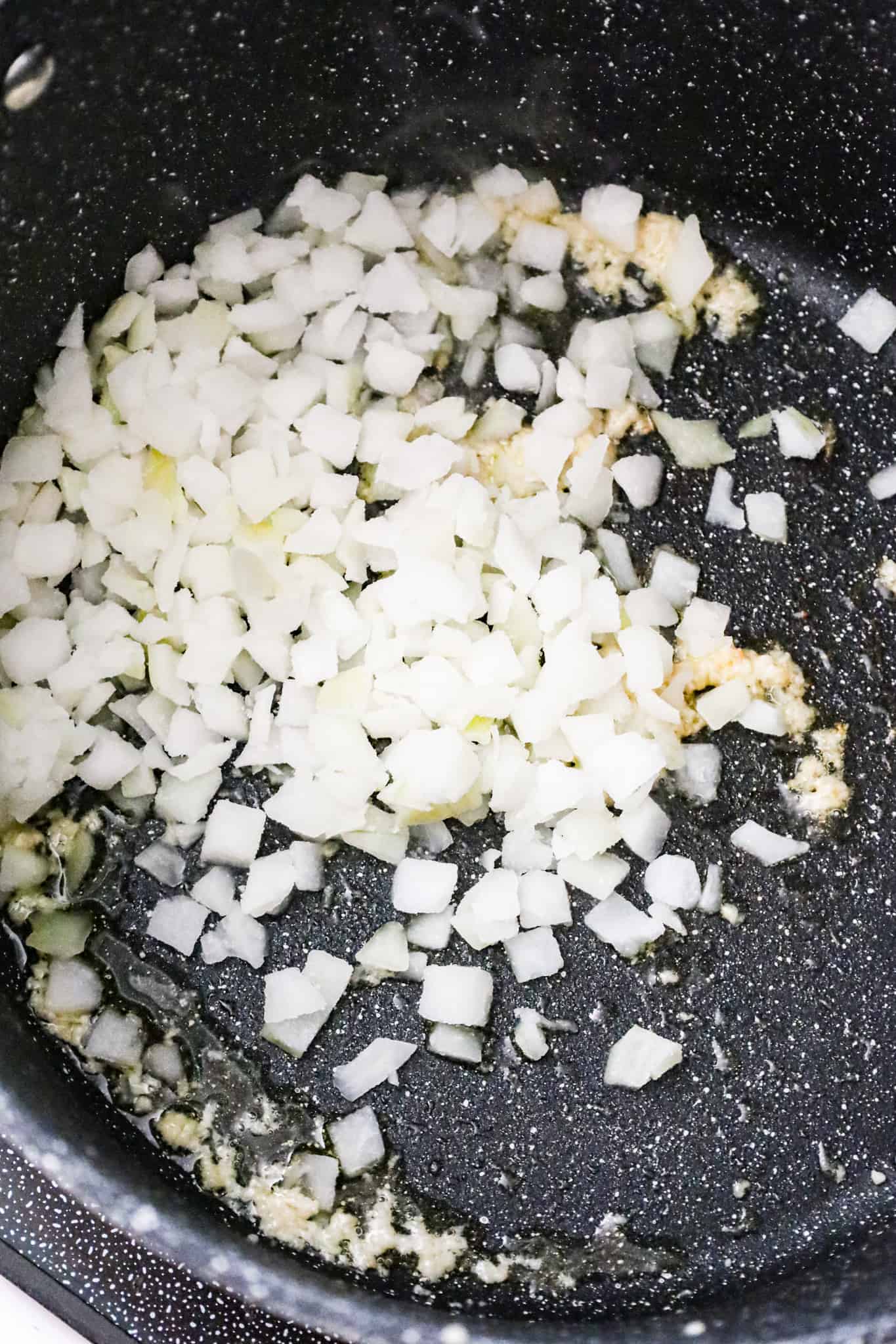 diced onions added to a pot with olive oil and garlic puree