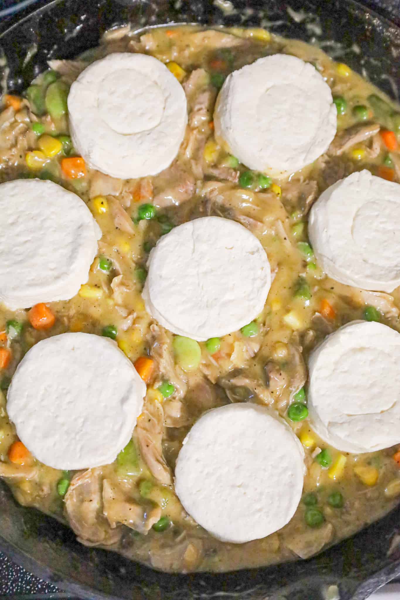 raw refrigerated biscuits on top of turkey and vegetable mixture in a skillet