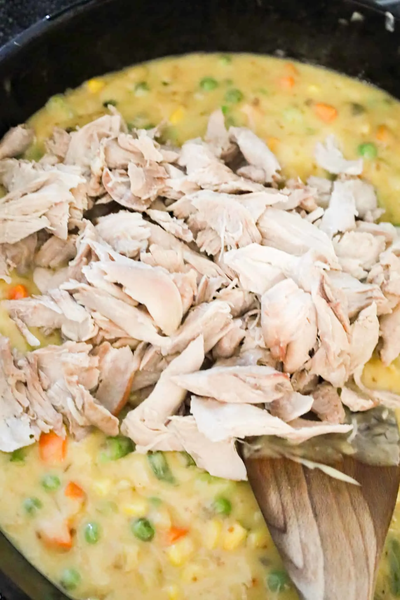 shredded turkey on top of vegetables and gravy mixture in a skillet