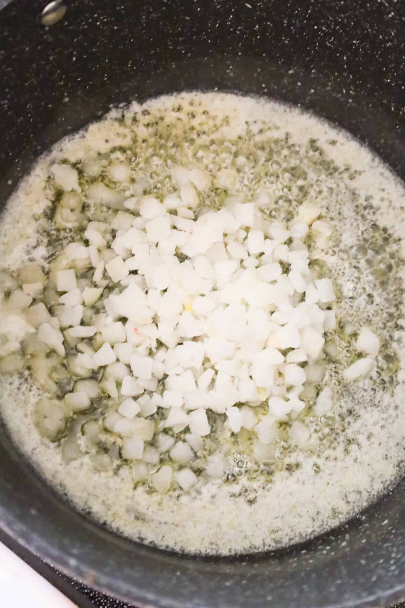 diced onions added to a pot with melted butter and garlic puree