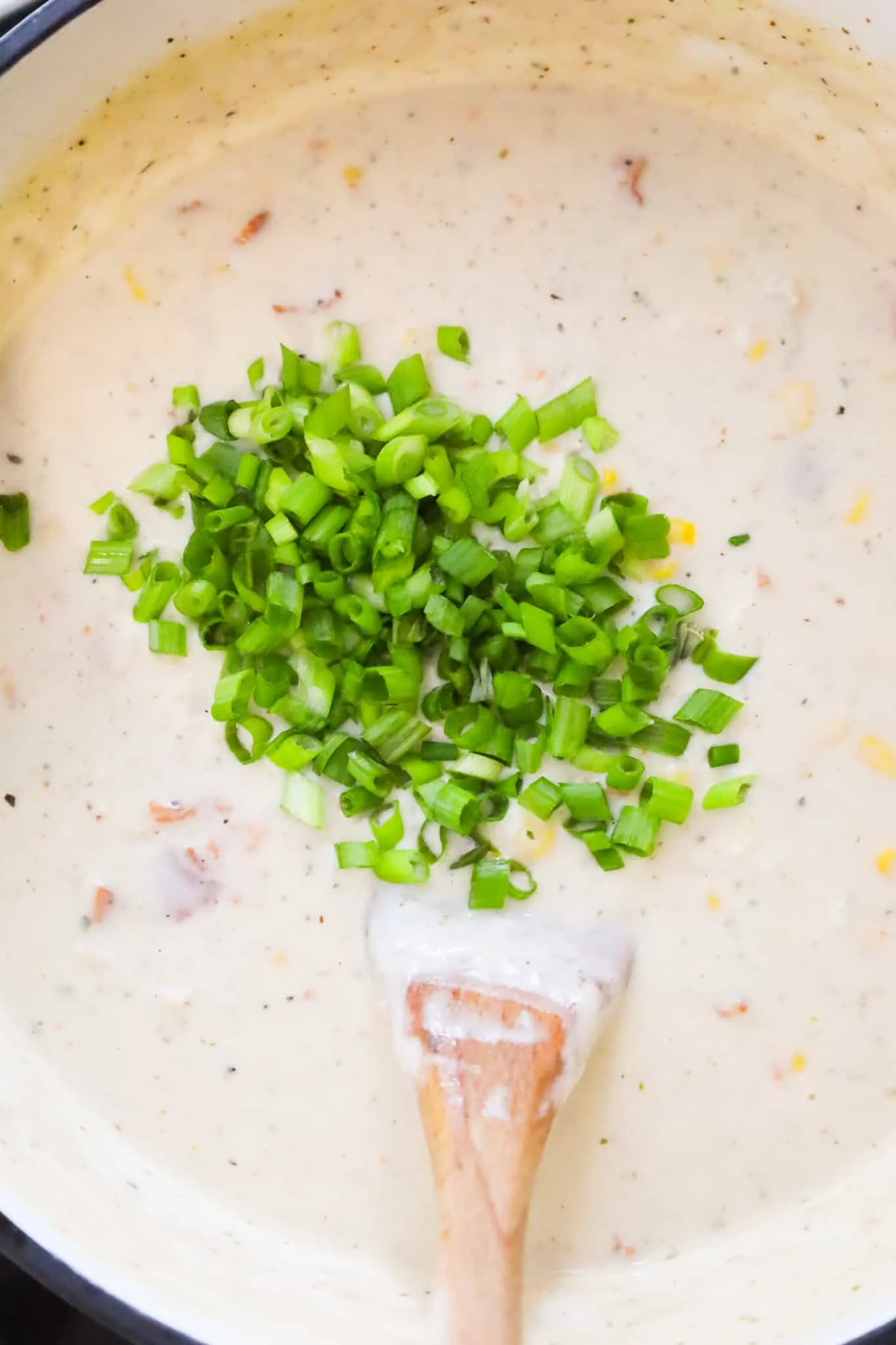chopped green onions on top of turkey corn chowder in a pot