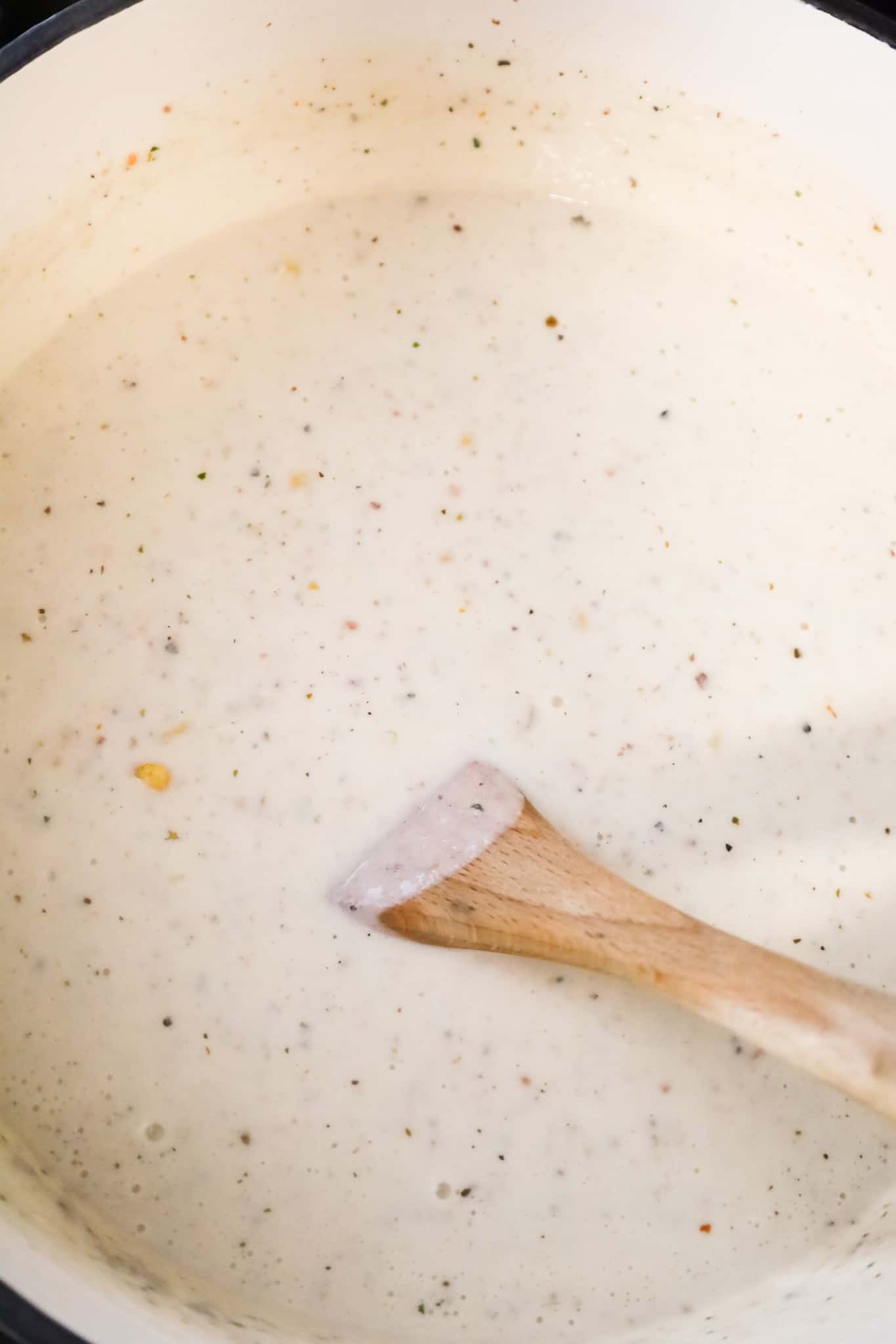 stirring corn into a creamy soup in a pot