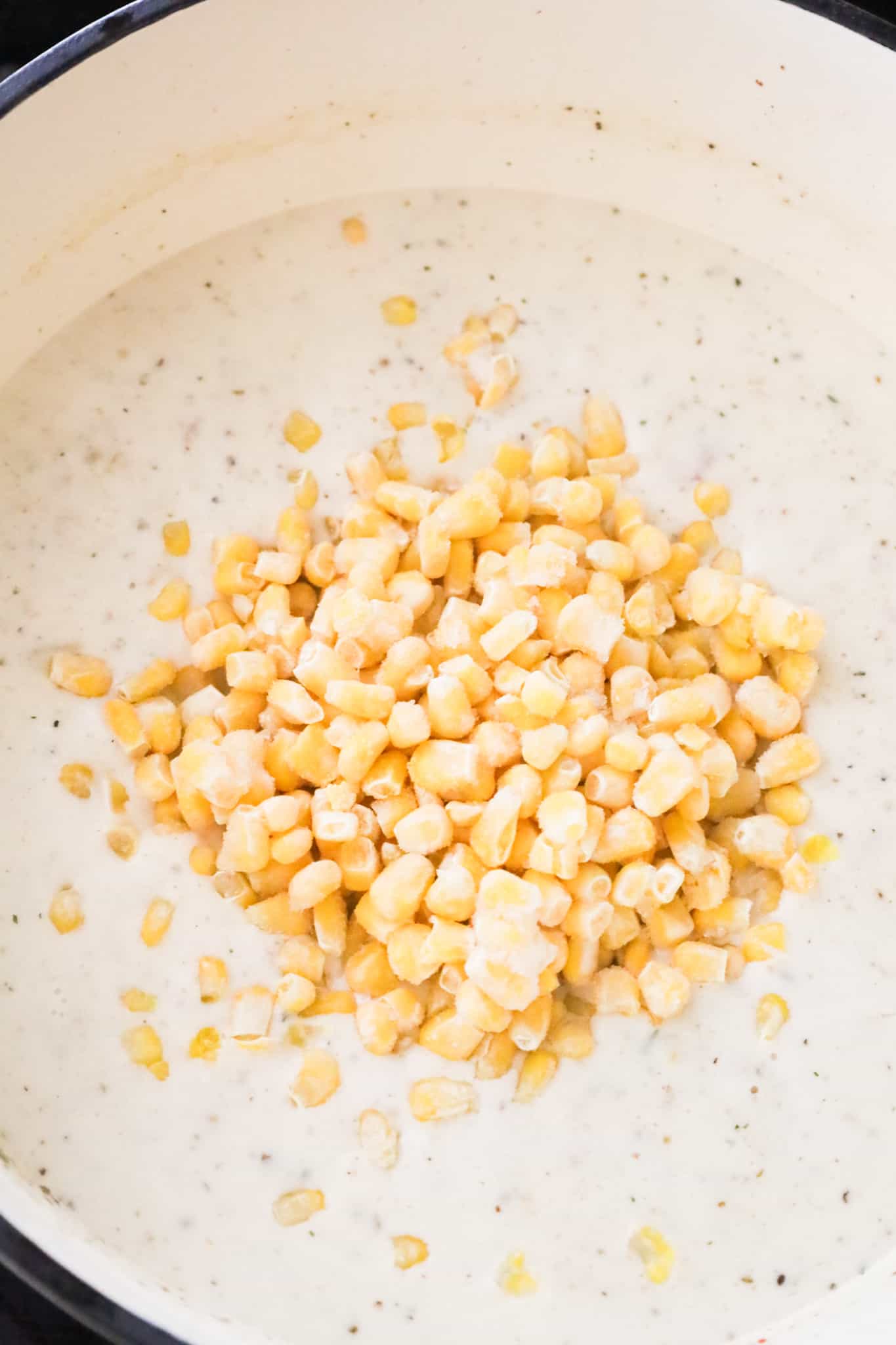 frozen corn kernels added to creamy soup in a pot