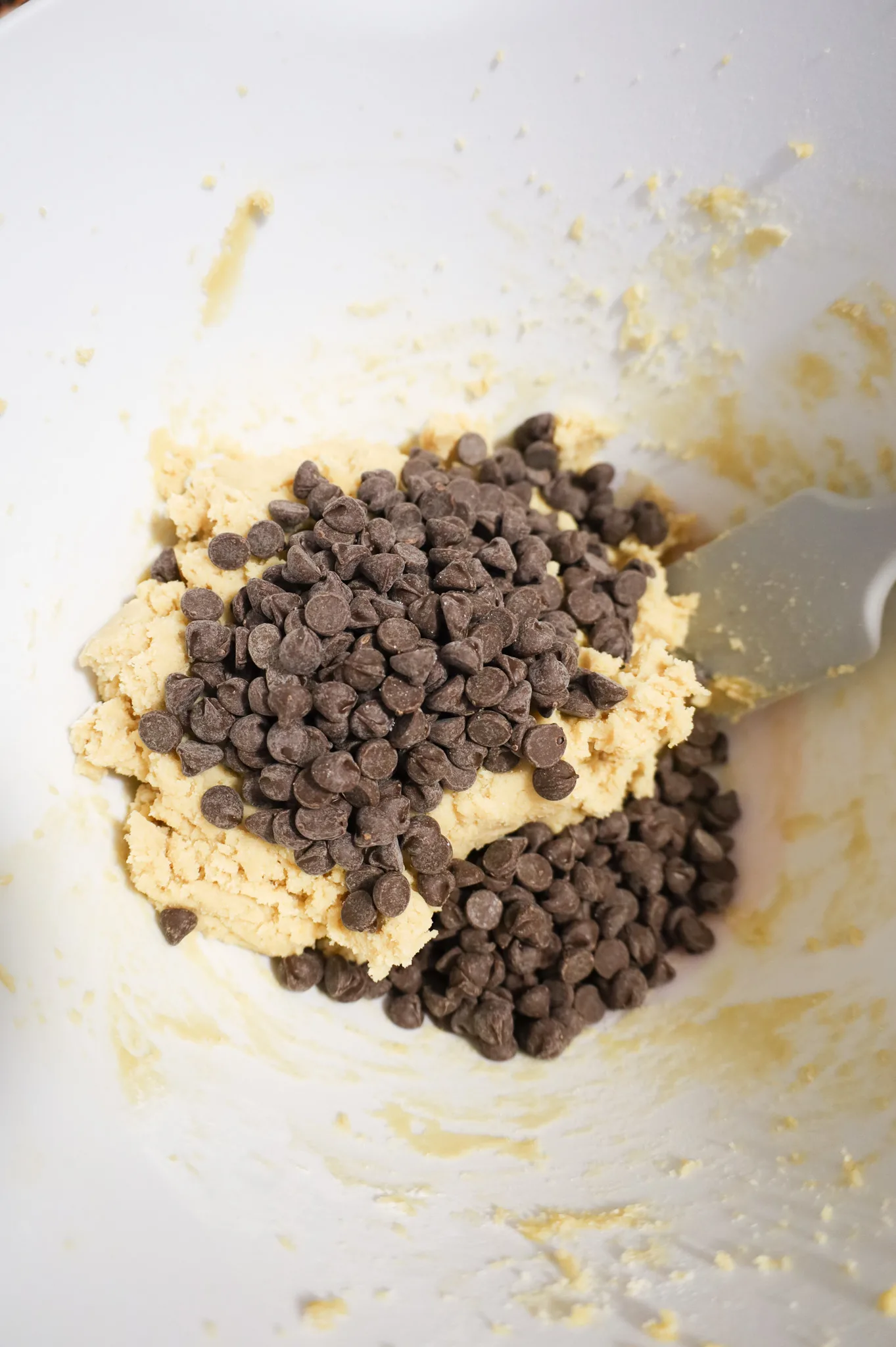 semi sweet chocolate chips on top of cookie dough in a mixing bowl