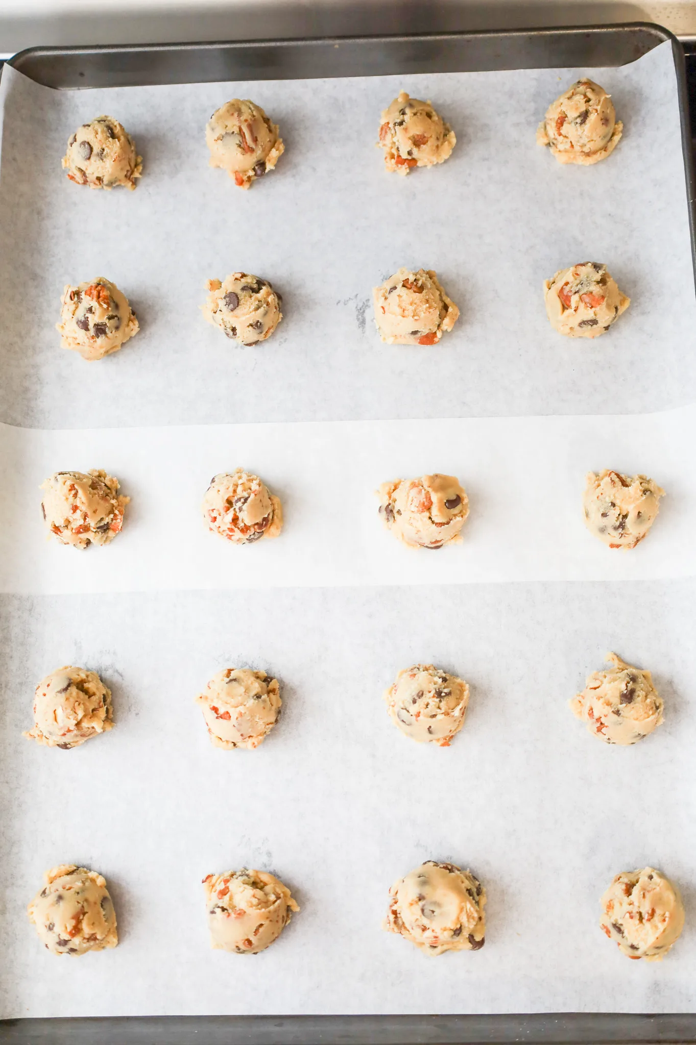 chocolate chip pecan cookie dough balls on a parchment lined baking sheet