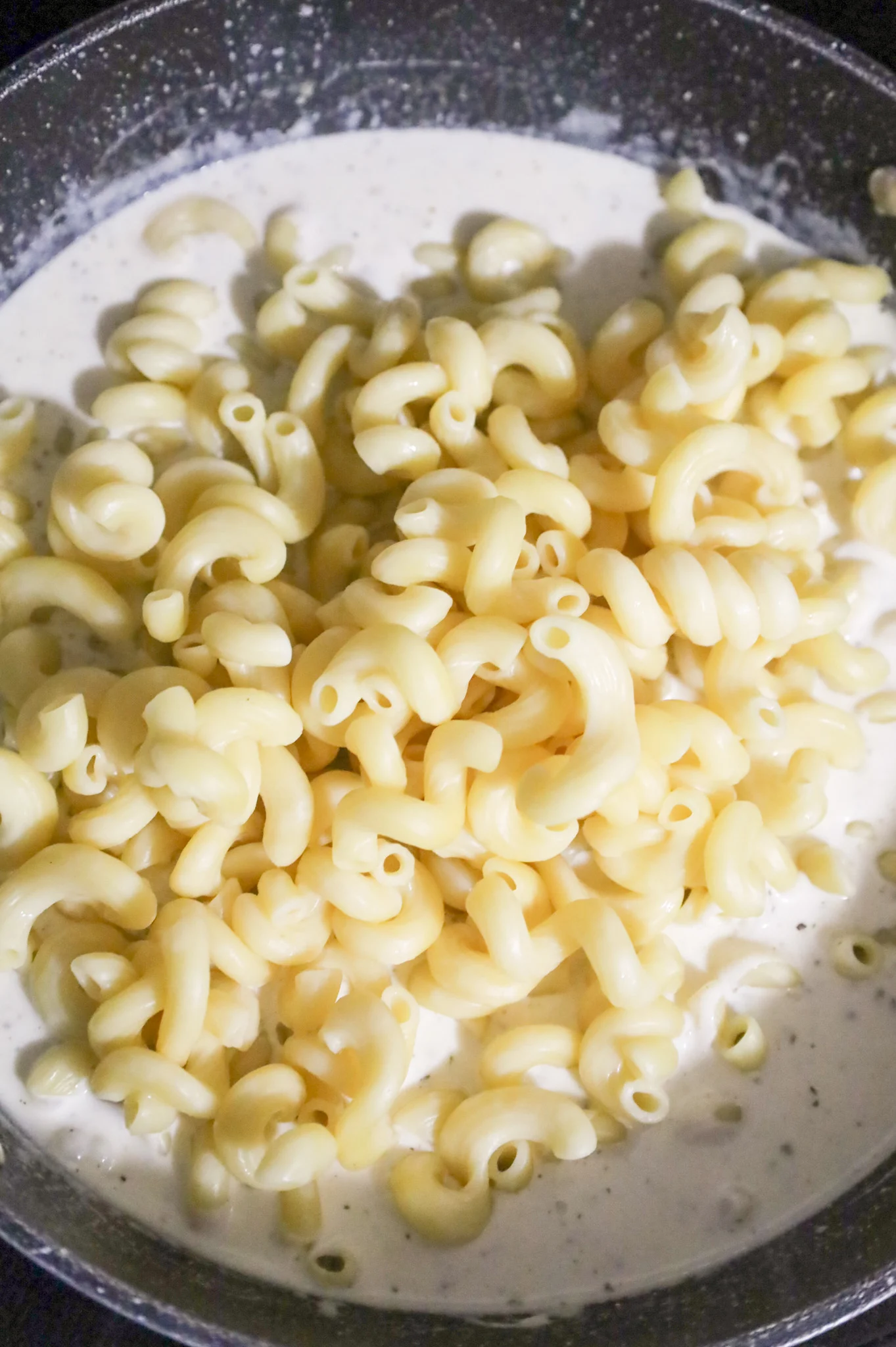 cooked cavatappi noodles added to a skillet with cream sauce