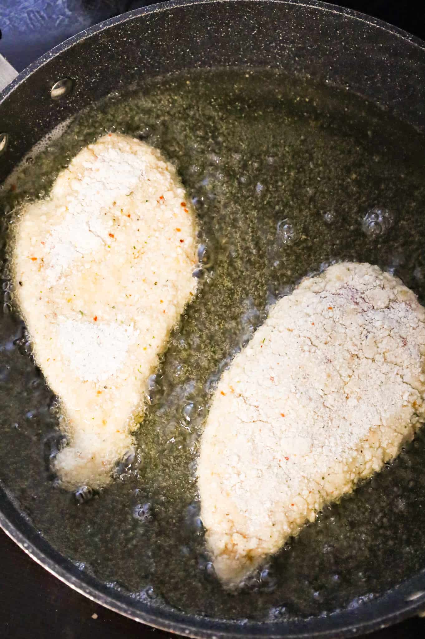 bread crumb coated chicken breasts frying in oil in a skillet