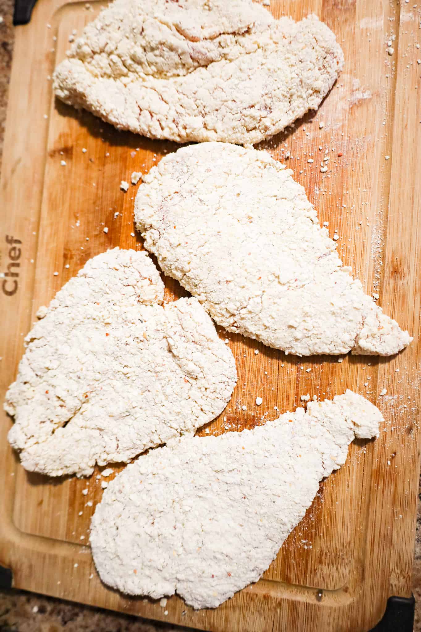 bread crumb coated chicken breasts on a cutting board
