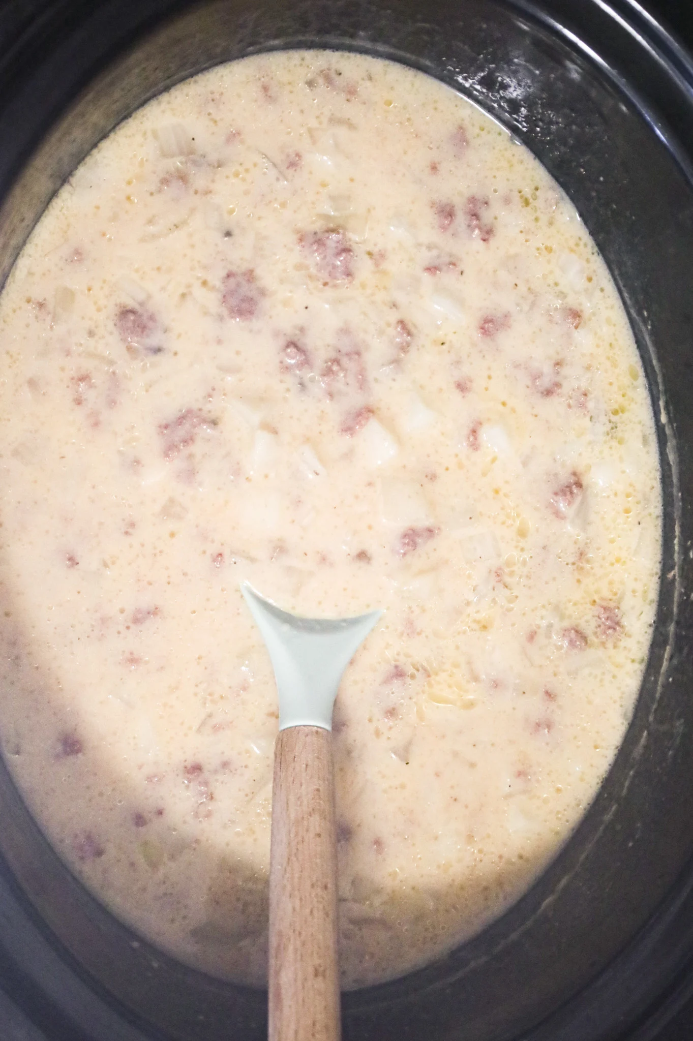 cheeseburger soup being stirred in a crock pot