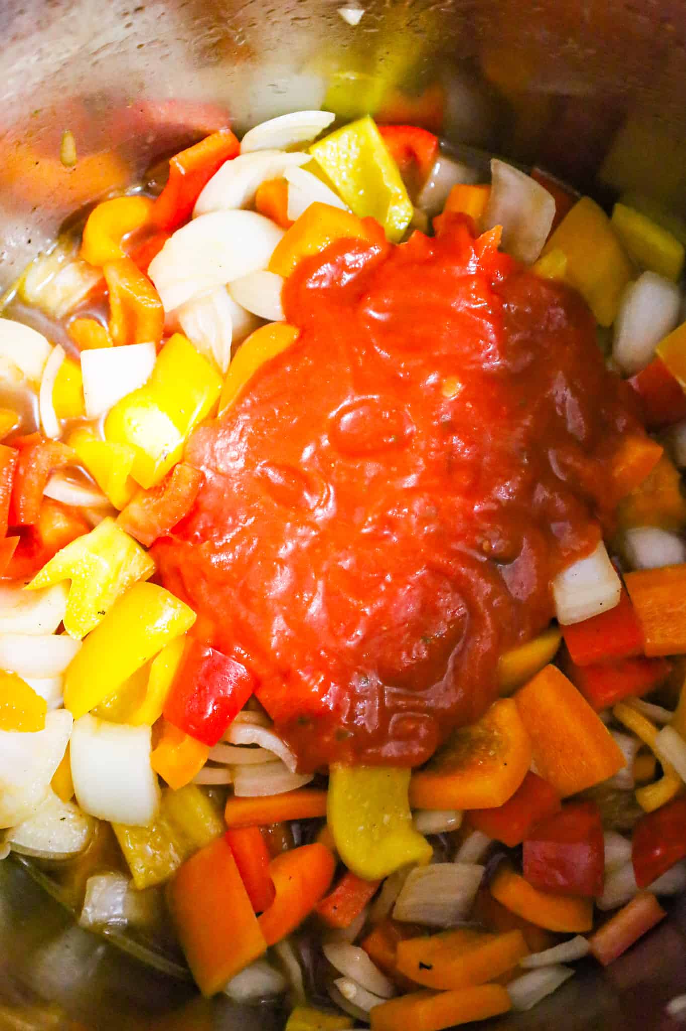marinara sauce on top of diced onions and diced peppers in an Instant Pot