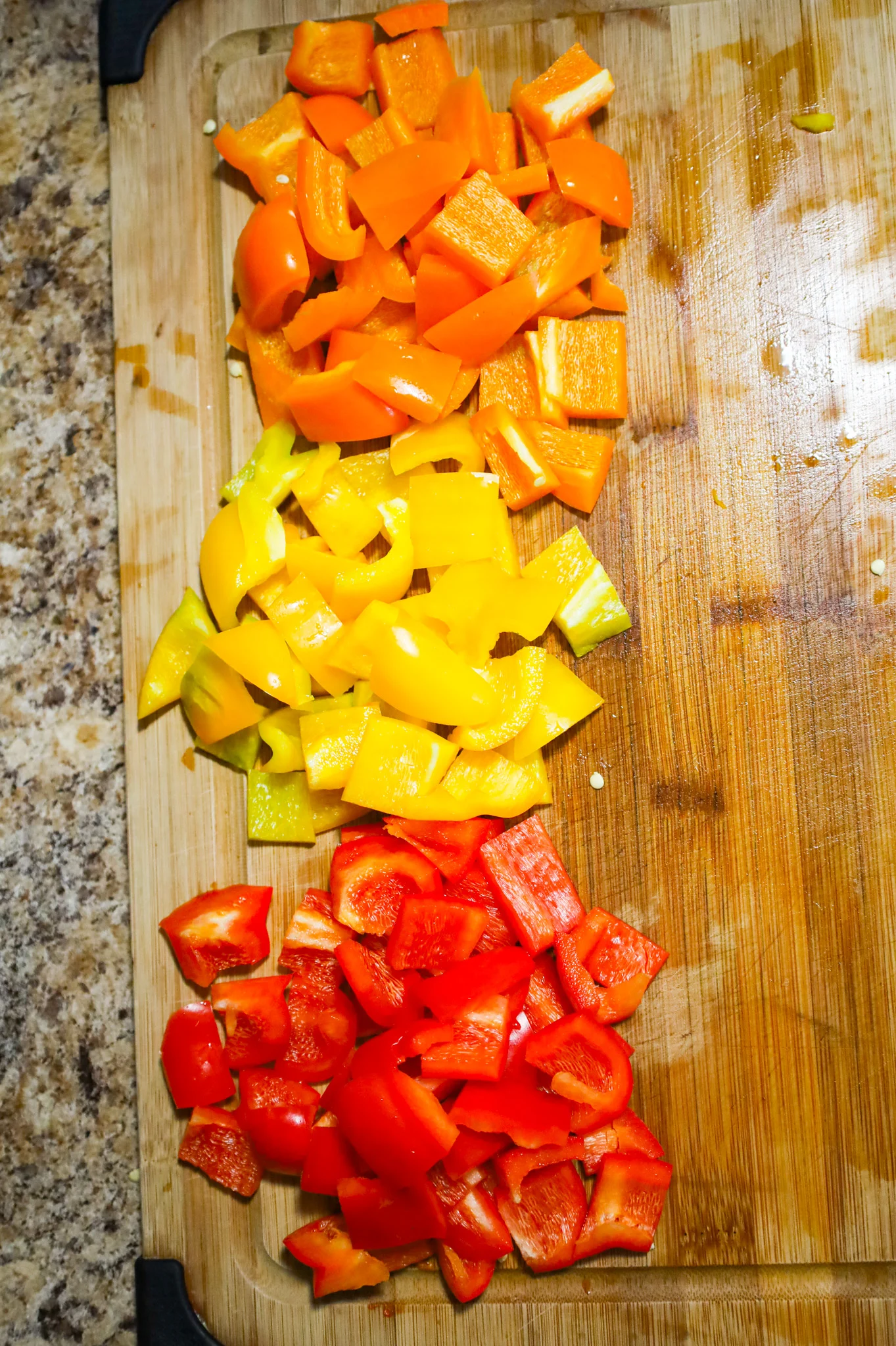 diced red, yellow and orange bell pepper on a cutting board