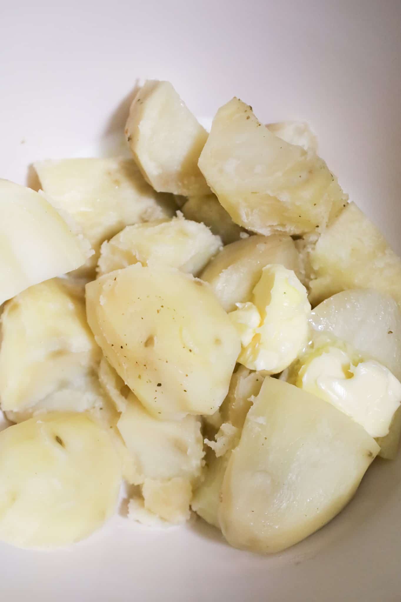 milk and butter added to cooked potatoes in a mixing bowl