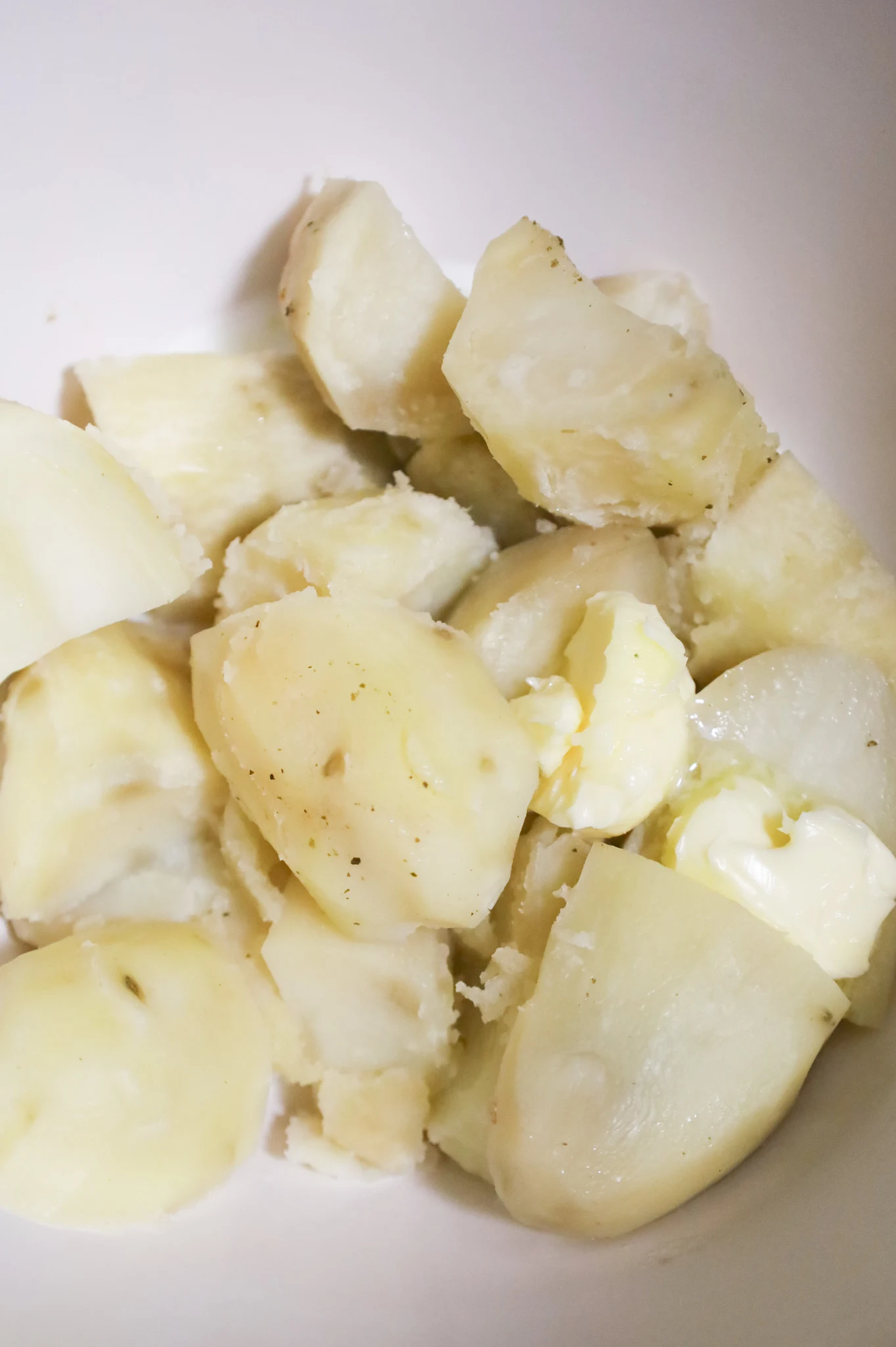 milk and butter added to cooked potatoes in a mixing bowl