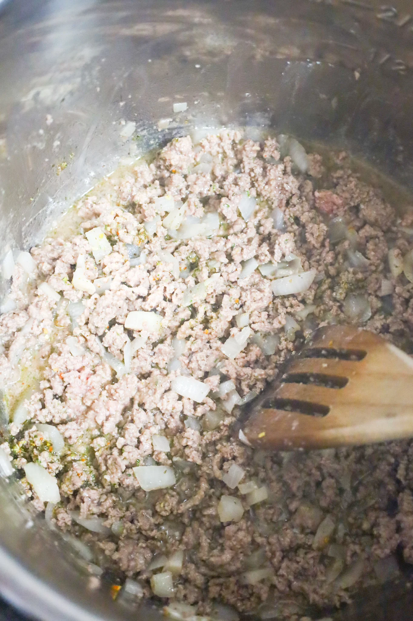 ground beef and diced onions cooking in an Instant Pot with water