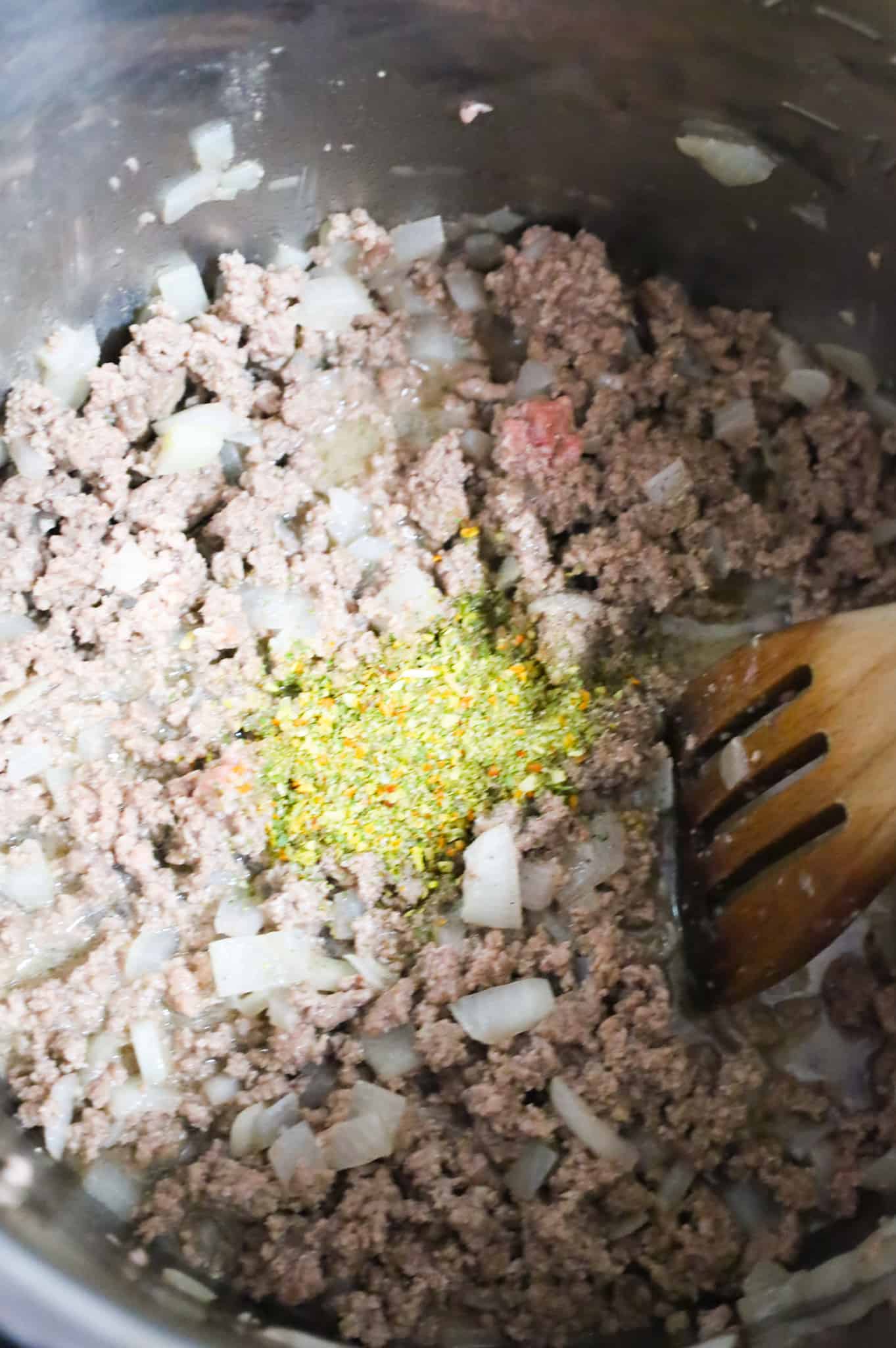 Italian seasoning, salt and pepper on top of cooked ground beef and diced onion mixture in an Instant Pot