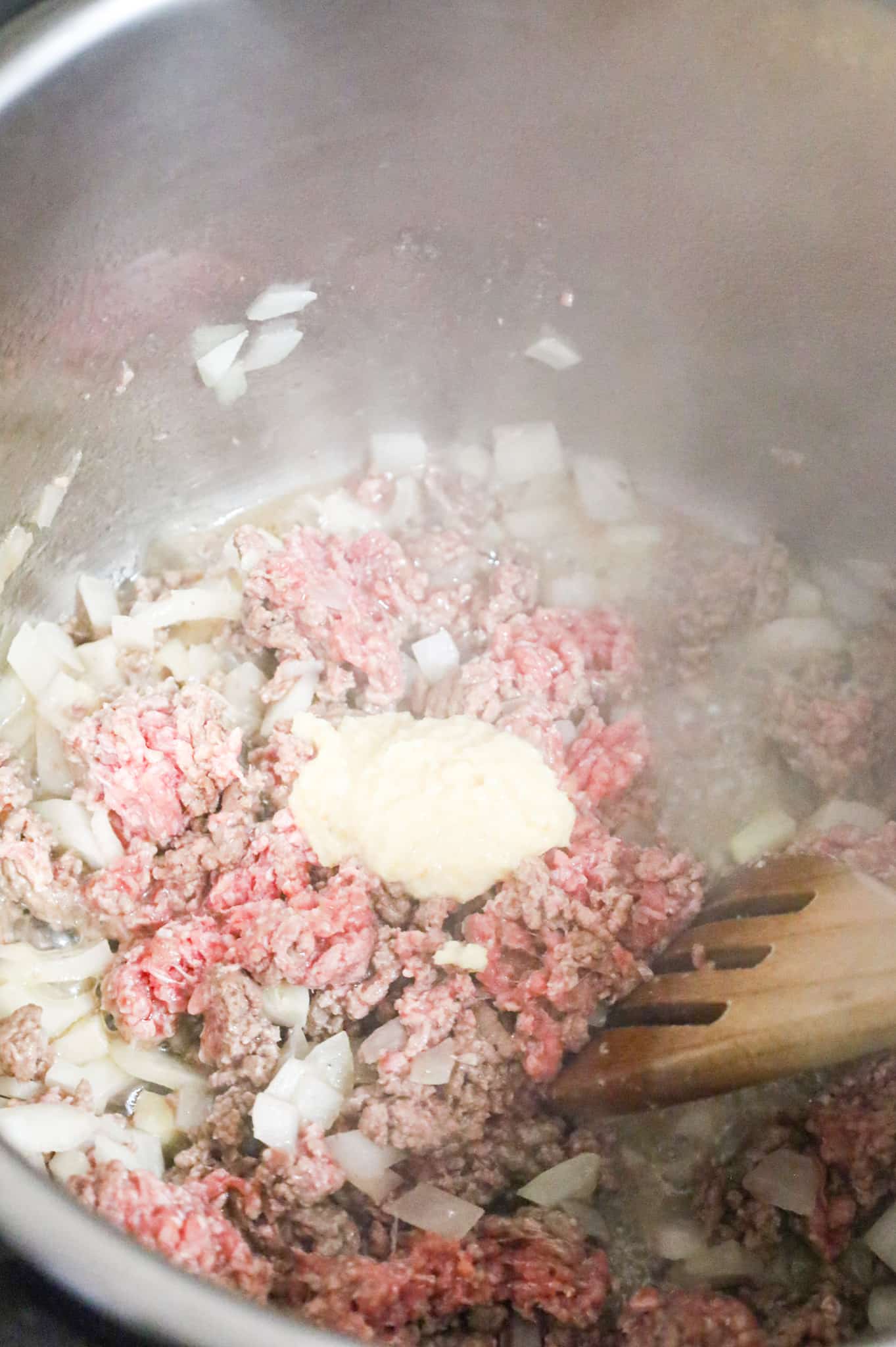 garlic puree on top of ground beef and diced onions in an Instant Pot