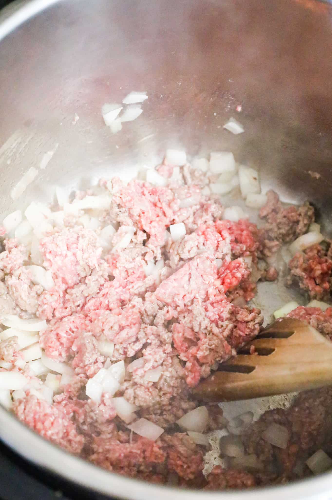 ground beef and diced onions being cooked in an Instant Pot