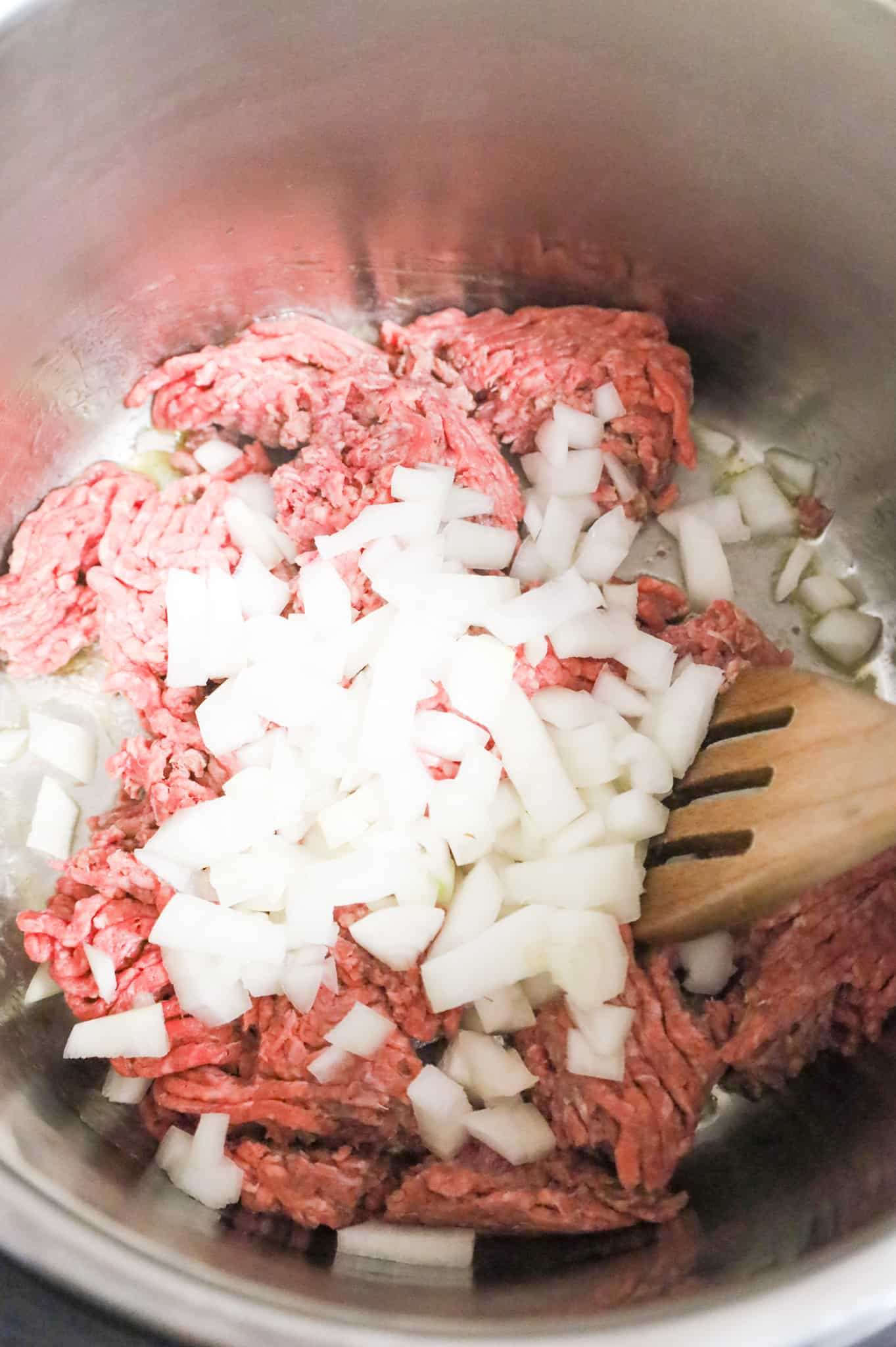 diced yellow onions on top of lean ground beef in an Instant Pot