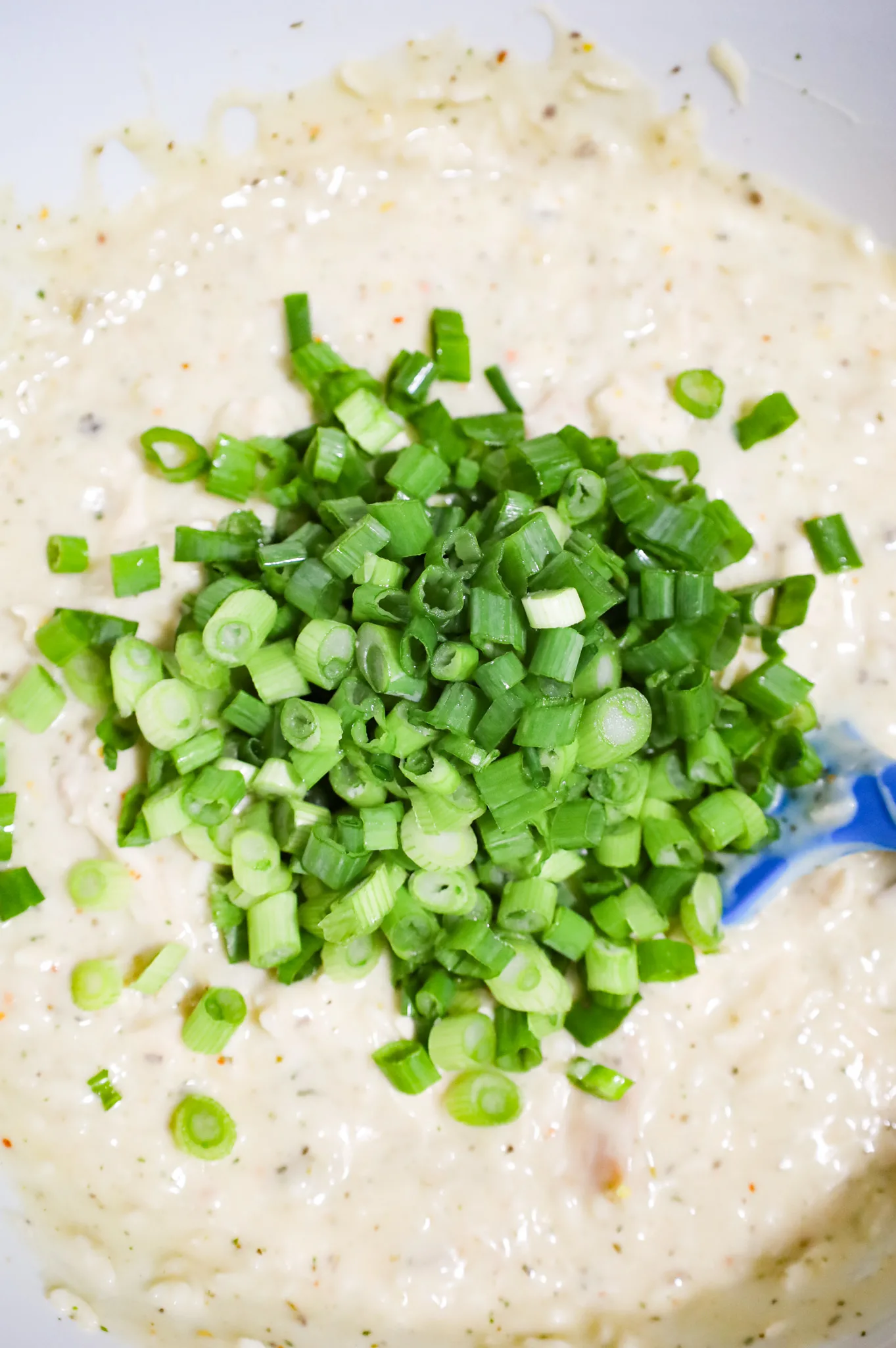chopped green onions on top of creamy chicken and rice mixture in a mixing bowl