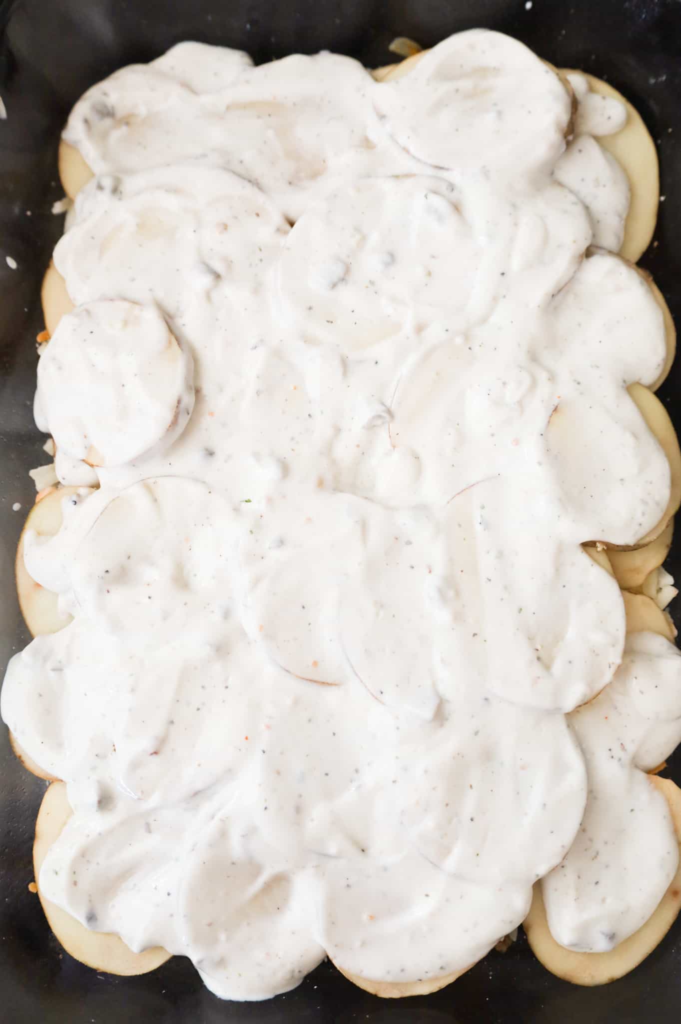 cream of mushroom soup mixture spread over sliced potatoes in a casserole dish