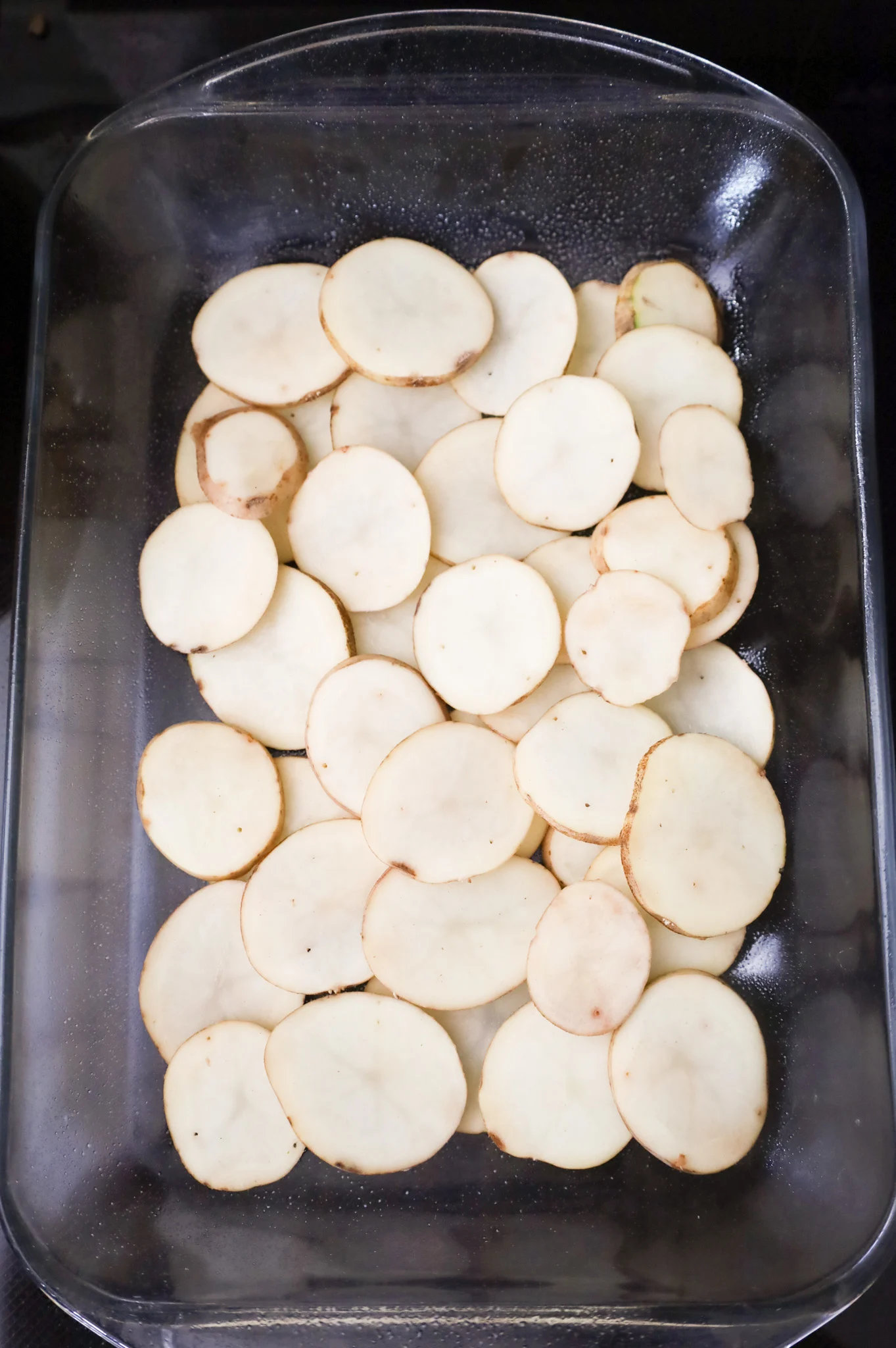 sliced potatoes in the bottom of a baking dish