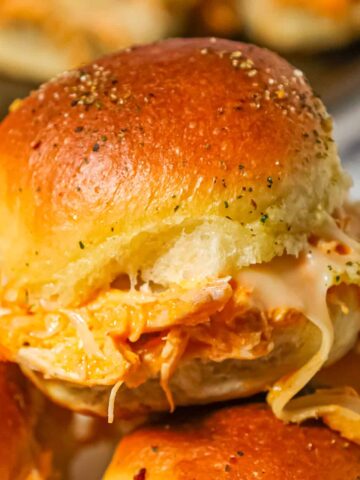 Buffalo Chicken Sliders are an easy weeknight dinner recipe using shredded rotisserie chicken, Buffalo sauce, ranch dressing, shredded cheese and chopped green onions all baked on dinner rolls.