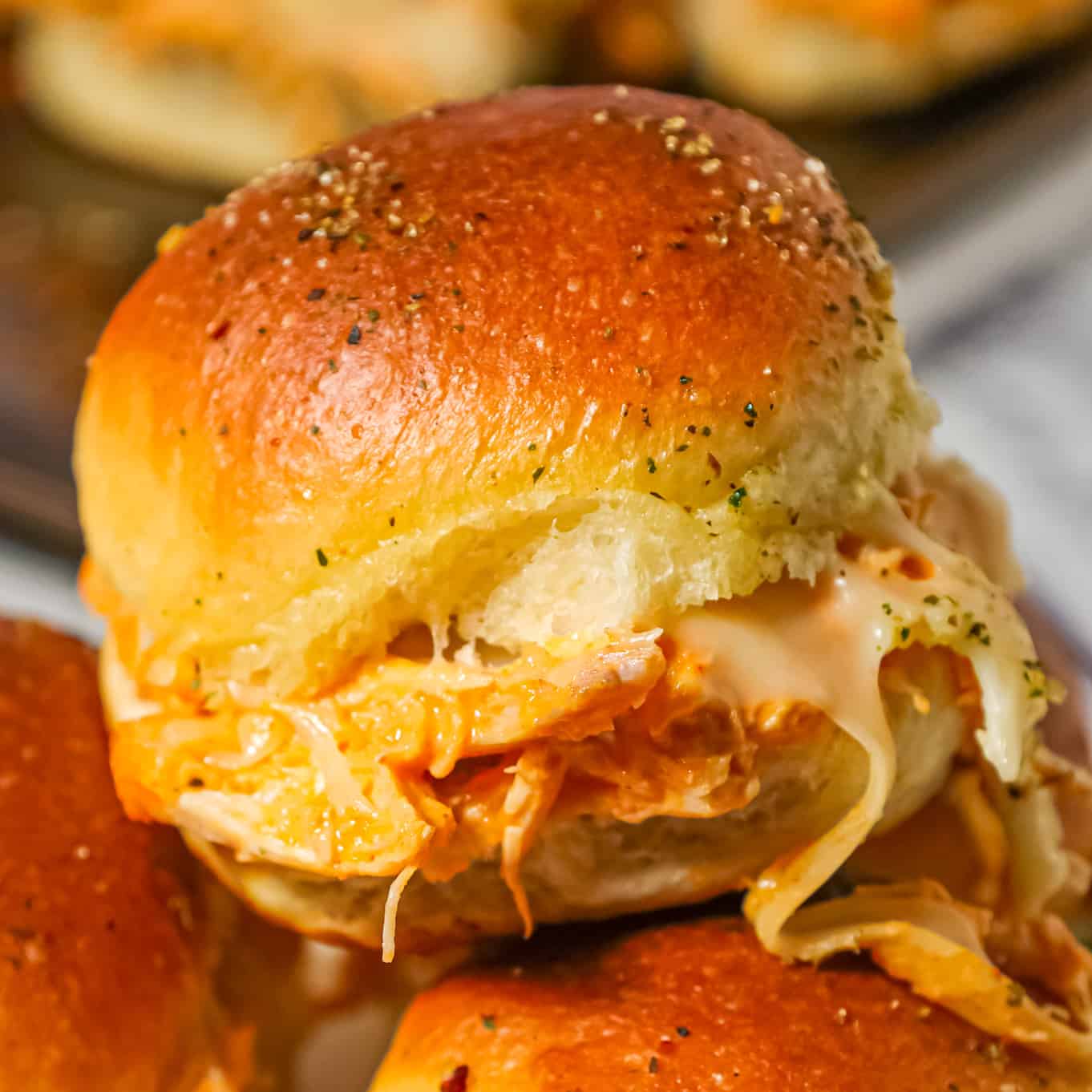 Buffalo Chicken Sliders are an easy weeknight dinner recipe using shredded rotisserie chicken, Buffalo sauce, ranch dressing, shredded cheese and chopped green onions all baked on dinner rolls.