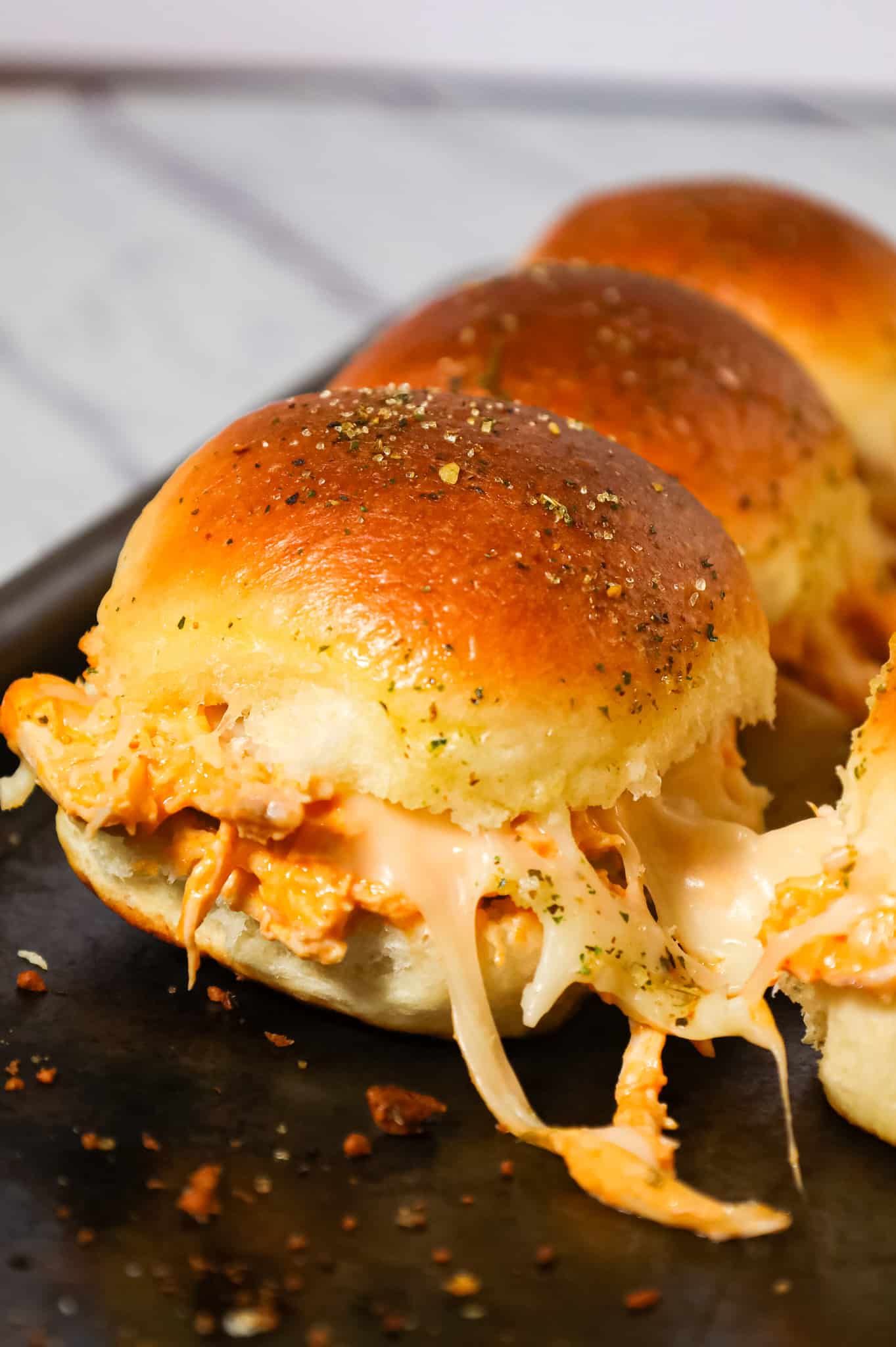 Buffalo Chicken Sliders are an easy weeknight dinner recipe using shredded rotisserie chicken, Buffalo sauce, ranch dressing, shredded cheese and chopped green onions all baked on dinner rolls.