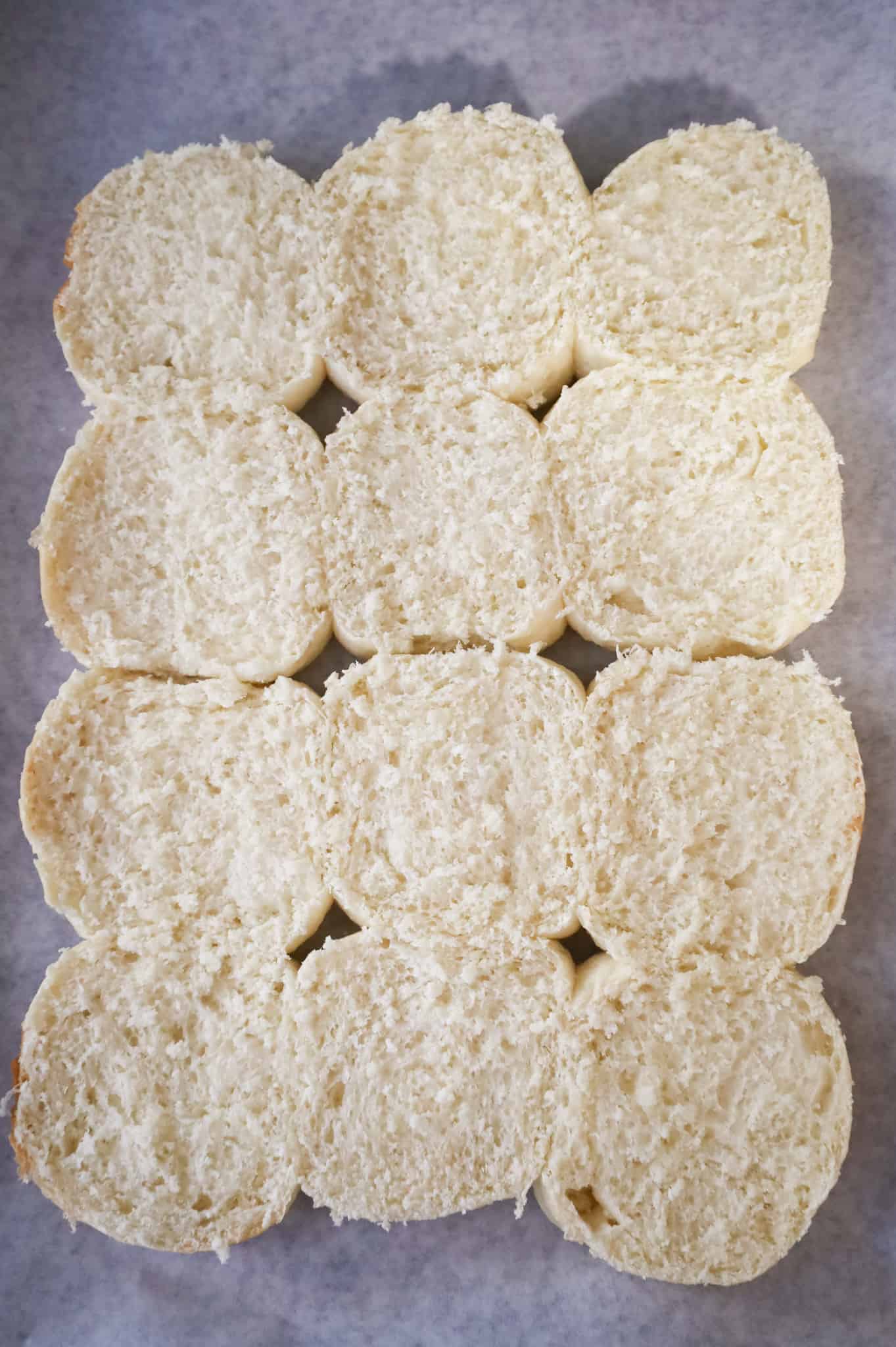 bottom halves of dinner rolls on a parchment lined baking sheet