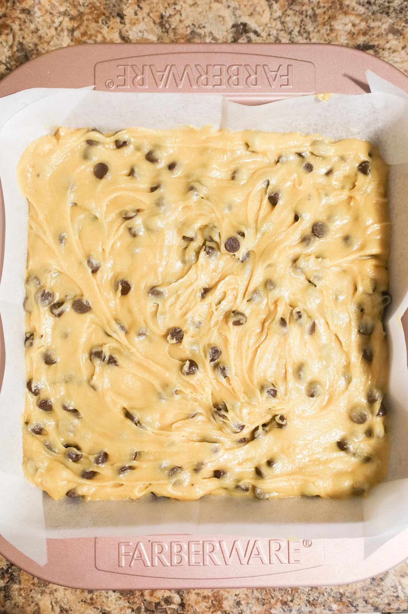 chocolate chip brownie batter in a parchment lined baking pan