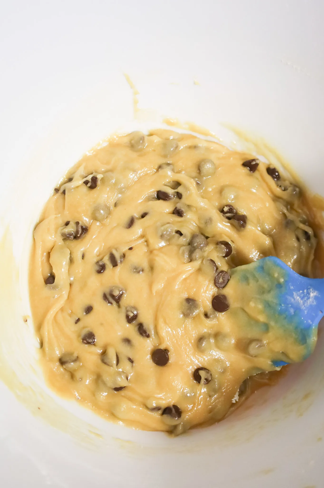 stirring chocolate chips into vanilla brownie batter in a mixing bowl