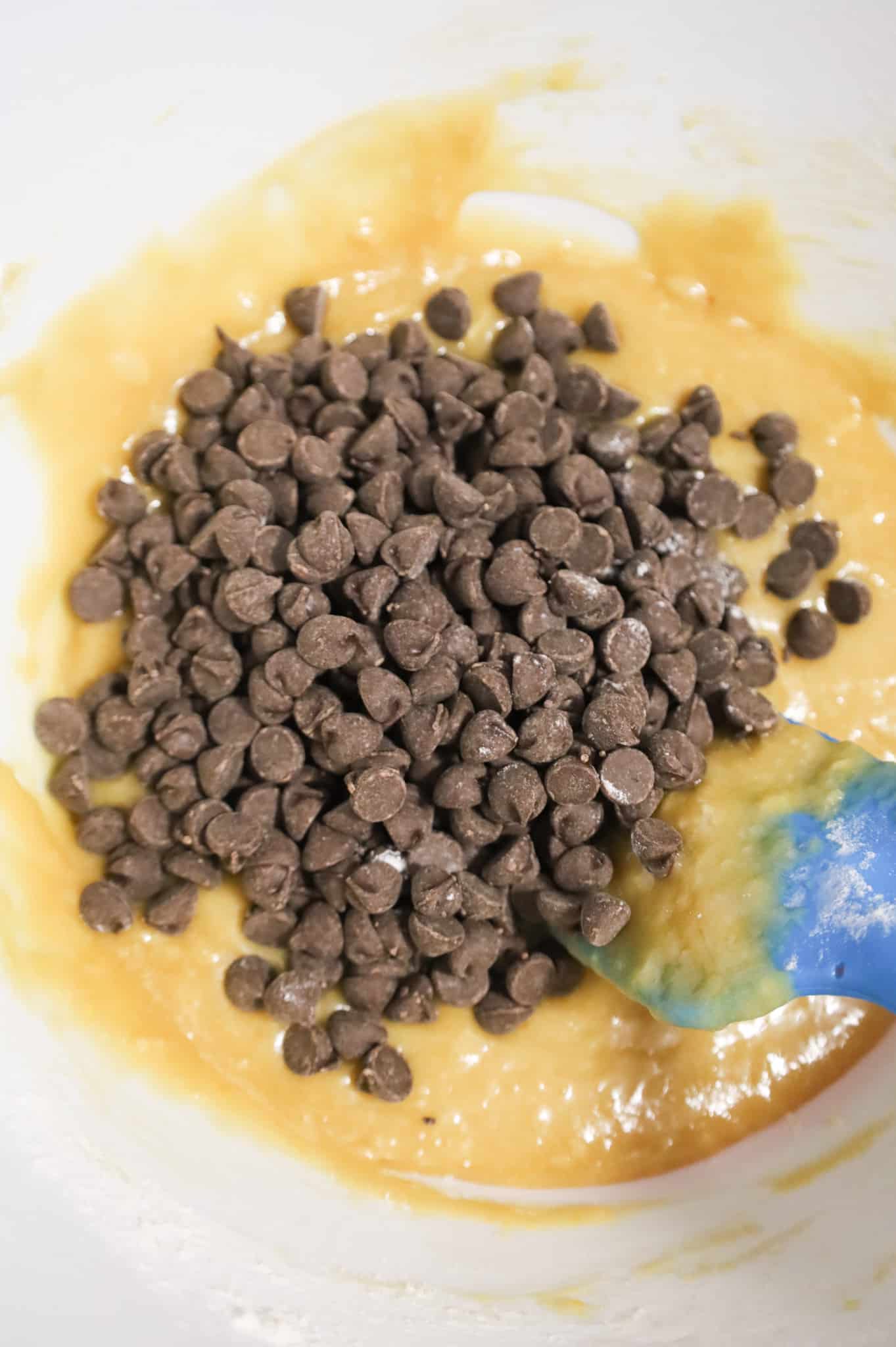 semi sweet chocolate chips on top of vanilla brownie batter in a mixing bowl