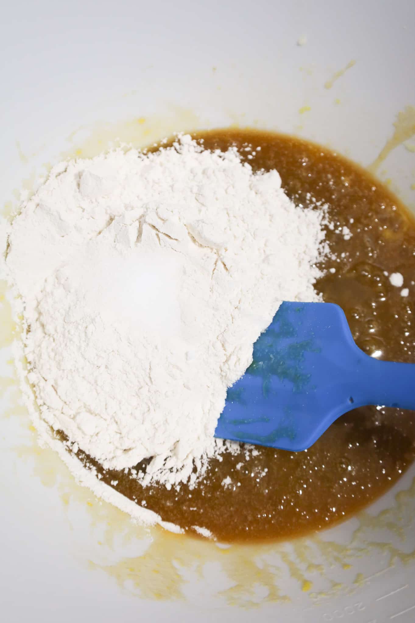 salt and flour on top of a sugar, butter and egg mixture in a mixing bowl