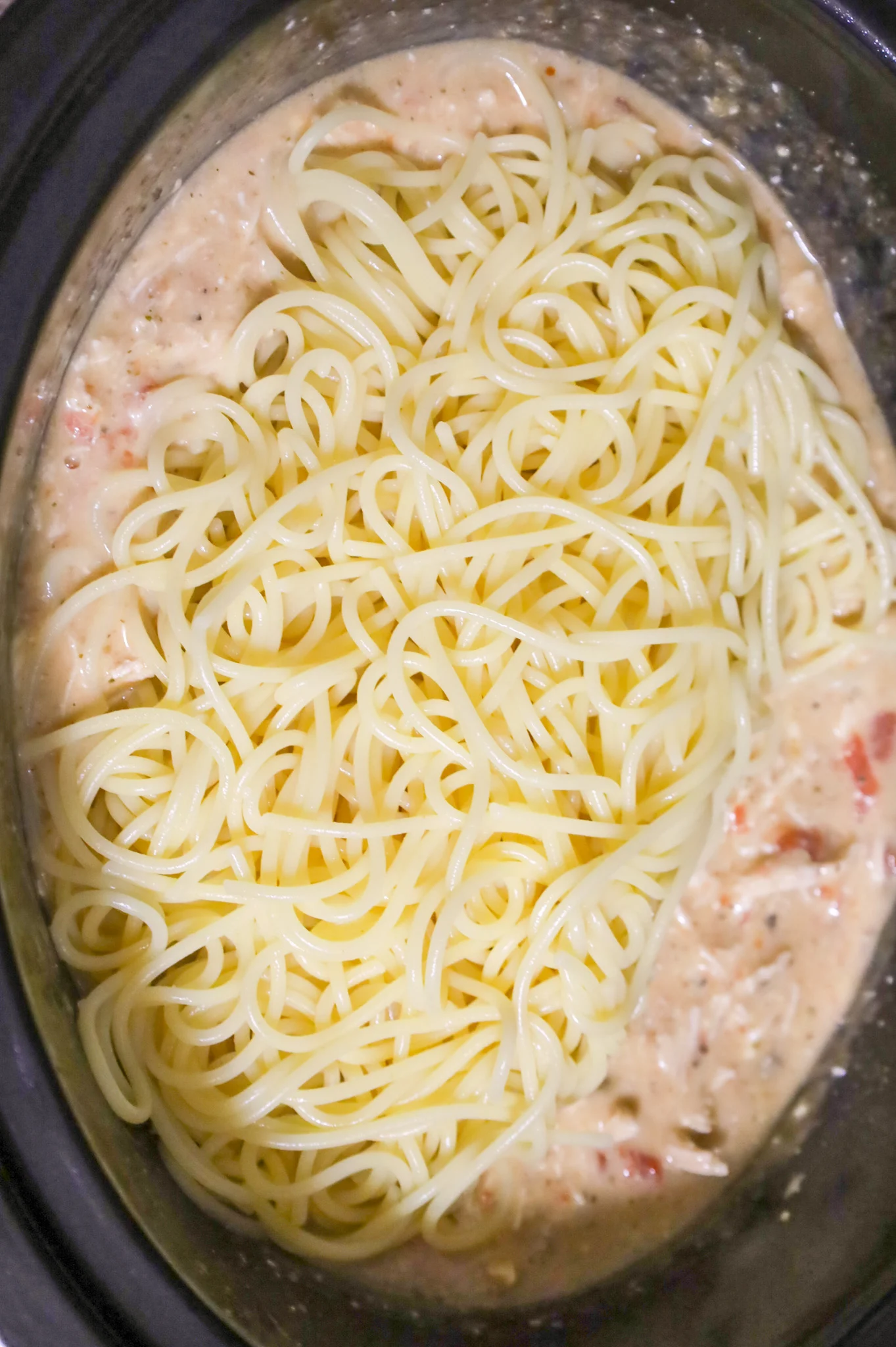 cooked spaghetti on top of cream soup mixture in a crock pot