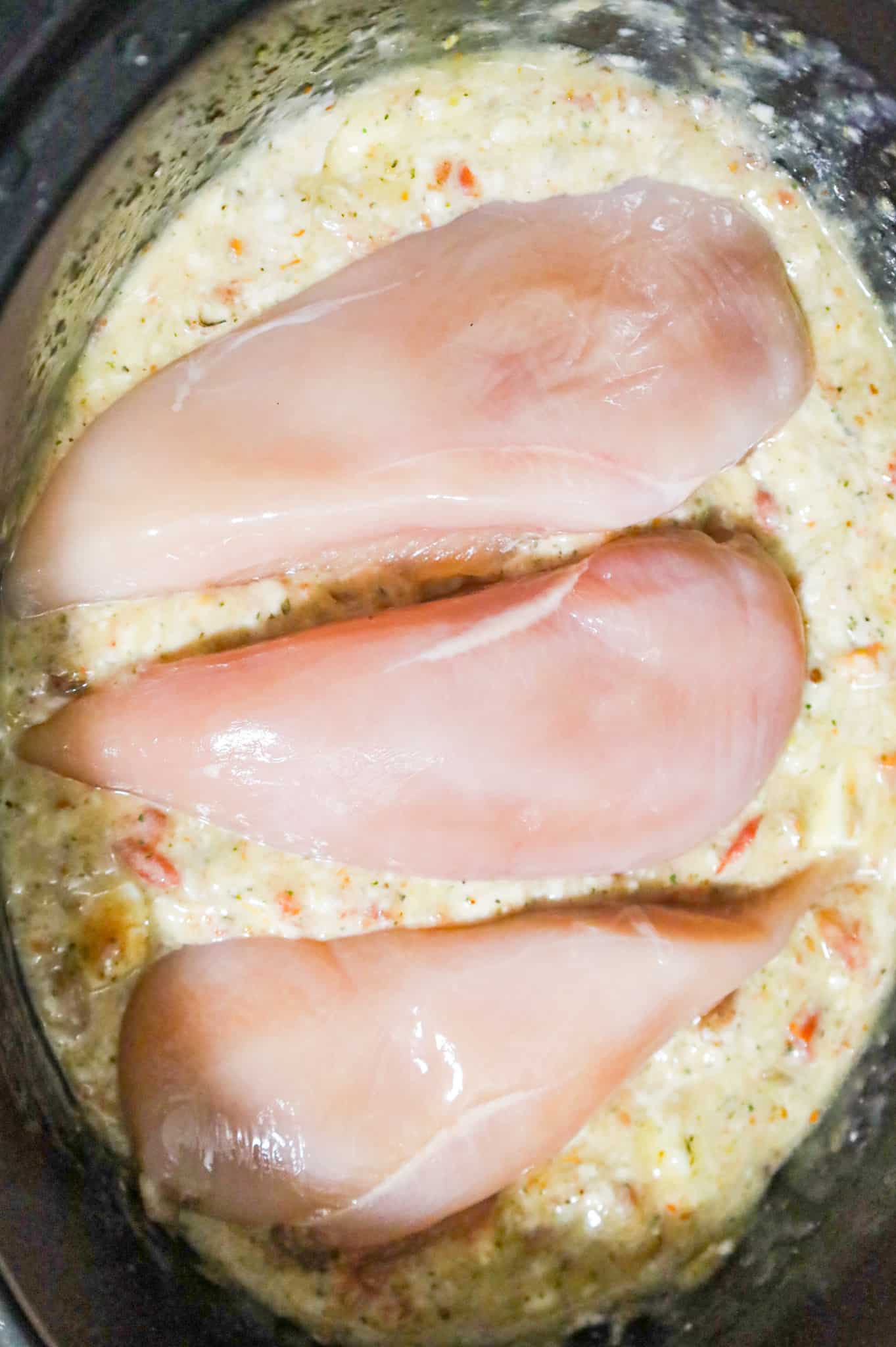 boneless, skinless chicken breasts on top of cream soup and rotel mixture in a crock pot