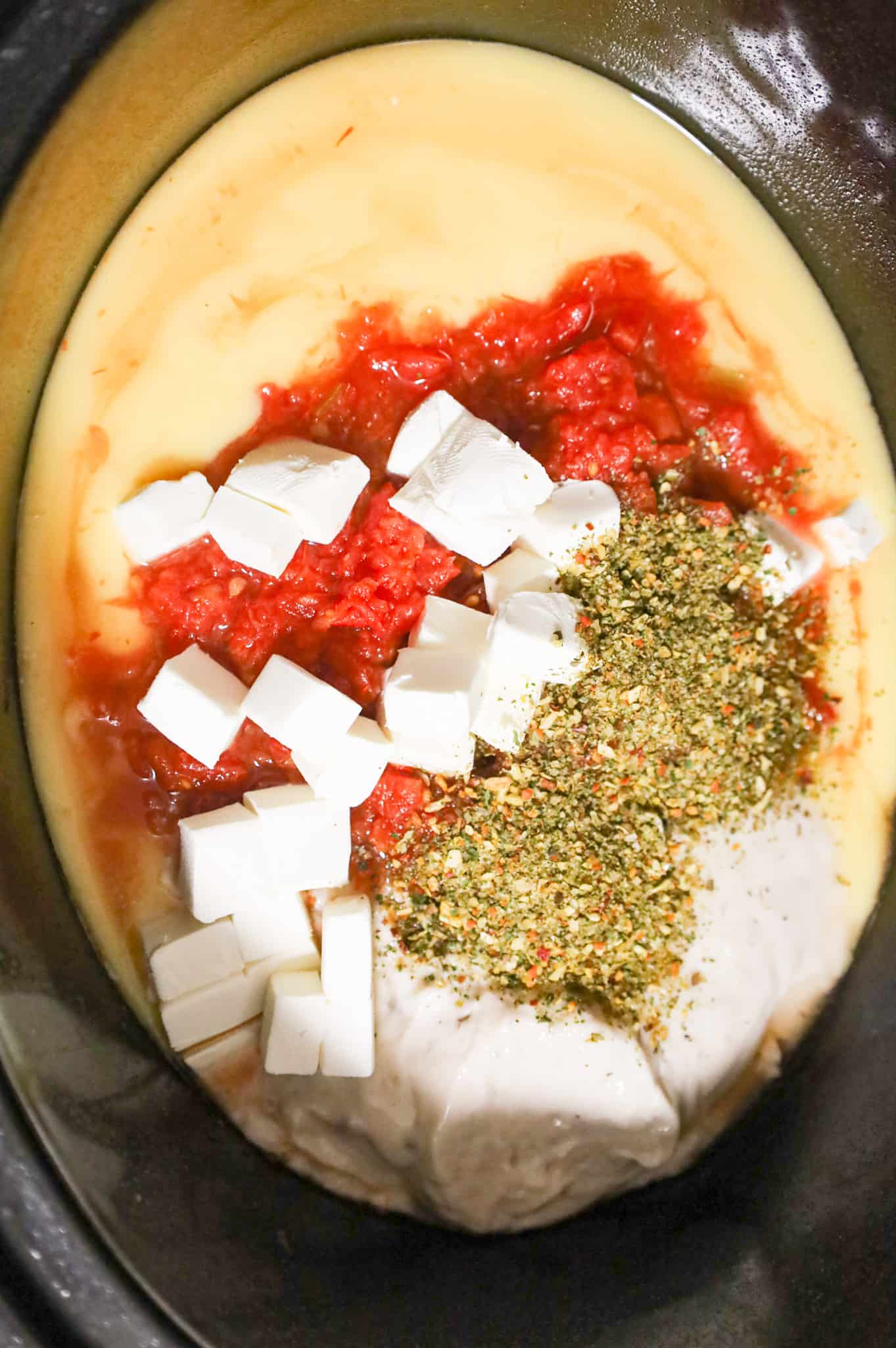 Italian seasoning, cubed cream cheese and rotel diced tomatoes on top of cream soups in a crock pot