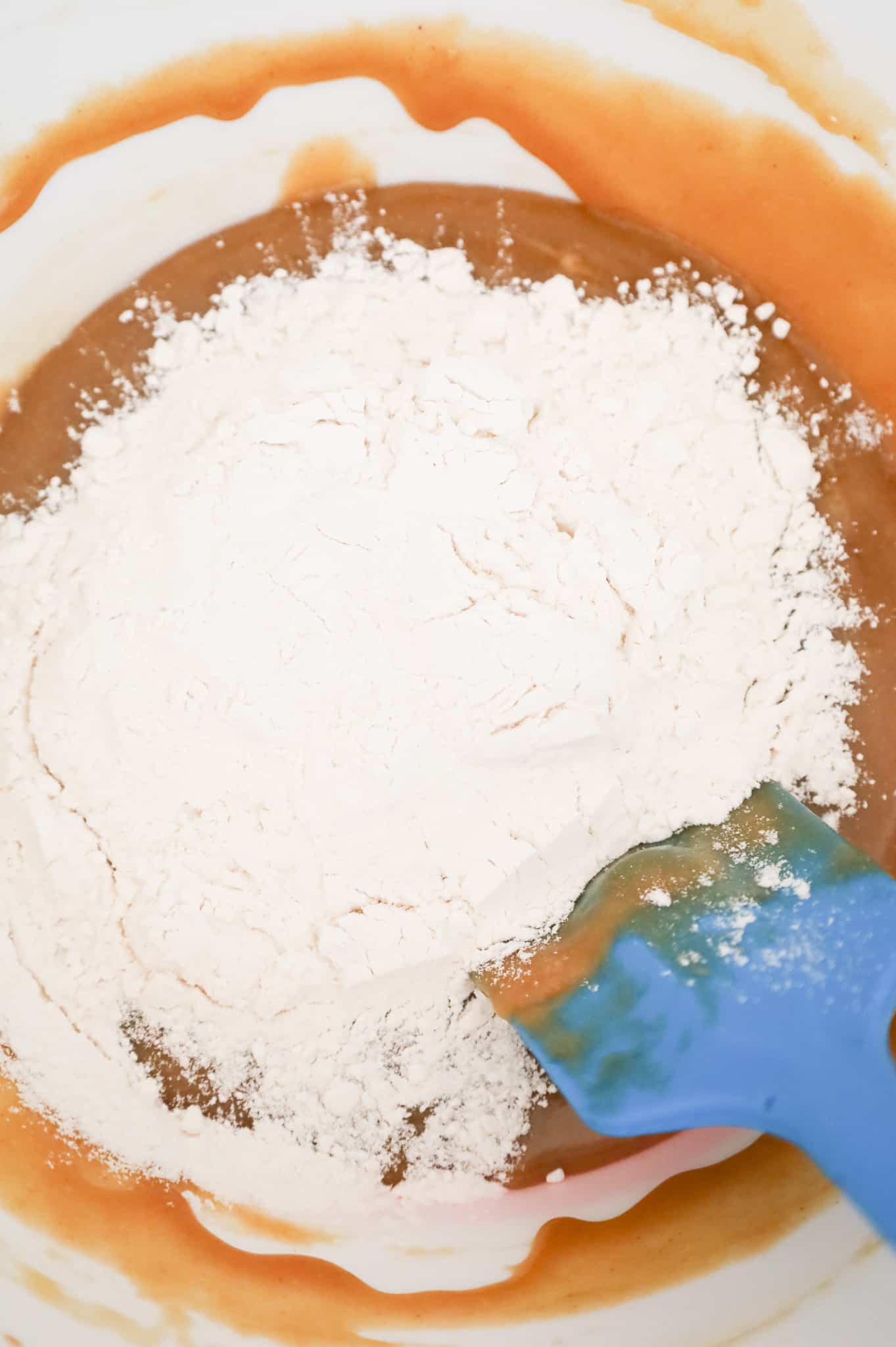 flour added to a mixing bowl with a peanut butter, butter and sugar mixture in a mixing bowl