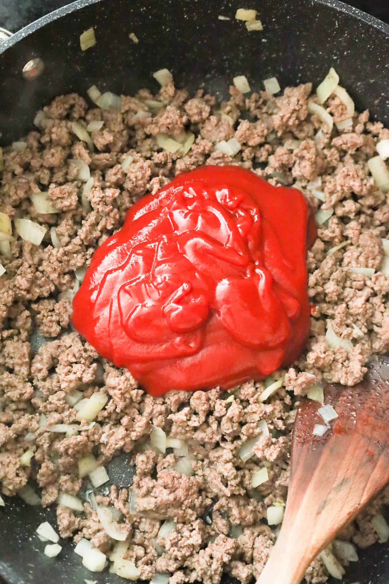ketchup on top of cooked ground beef in a skillet
