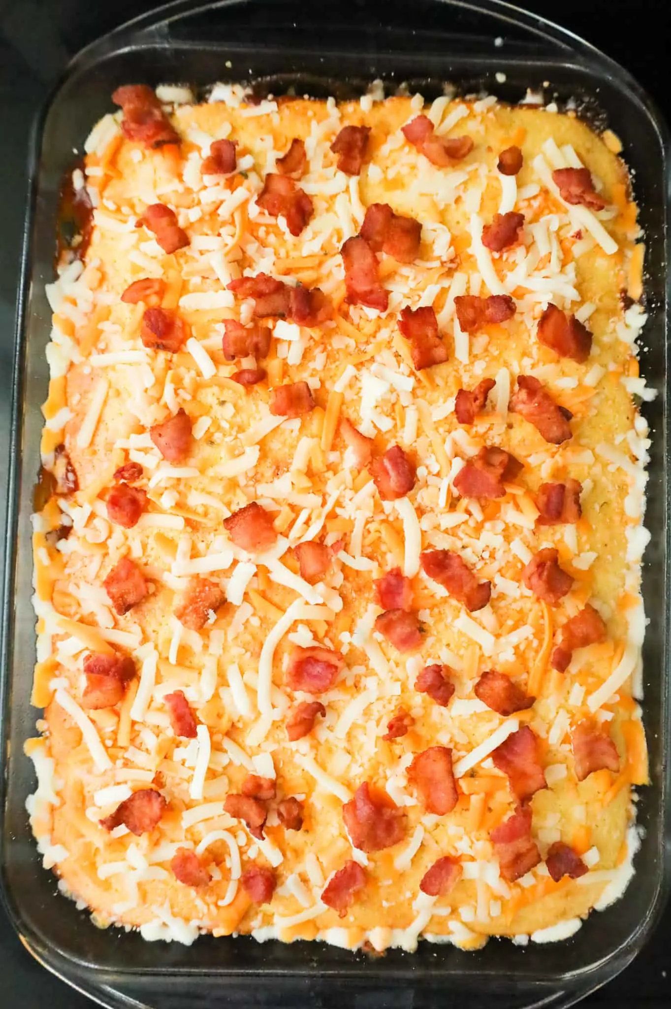 crumbled bacon and shredded cheese on top of cornbread casserole