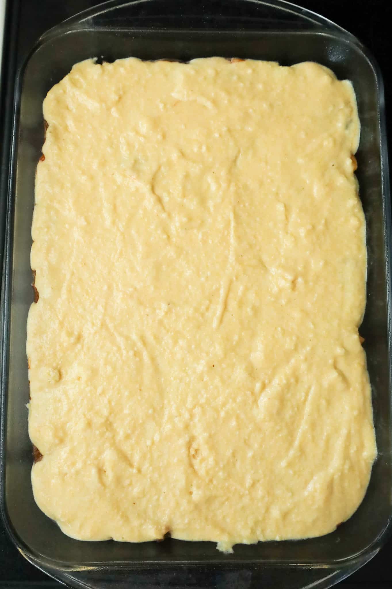 jiffy cornbread batter on top of ground beef mixture in a baking pan